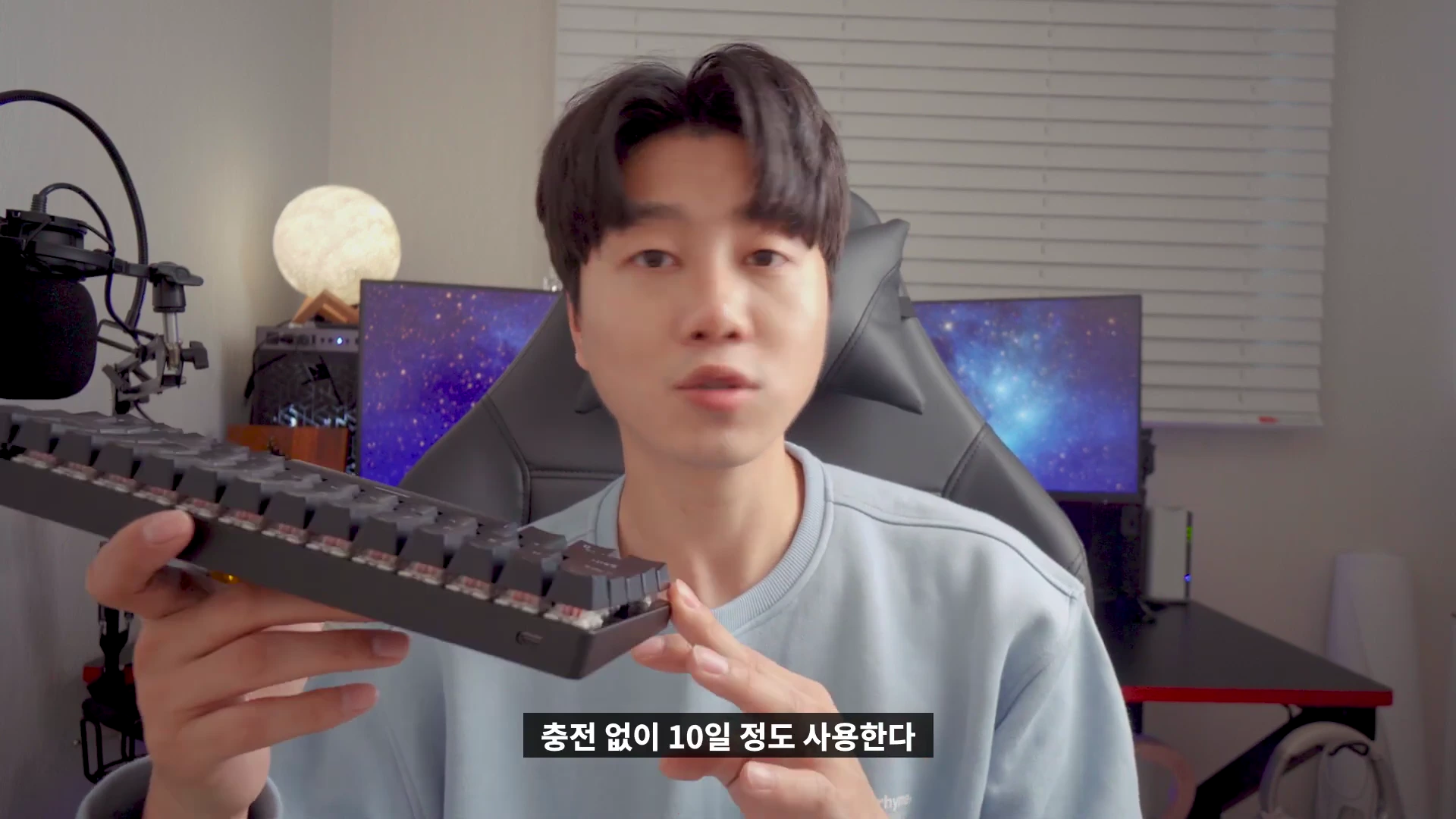 실내에서 한 남성이 검은색 미니 기계식 키보드를 손에 들고 설명하고 있는 모습