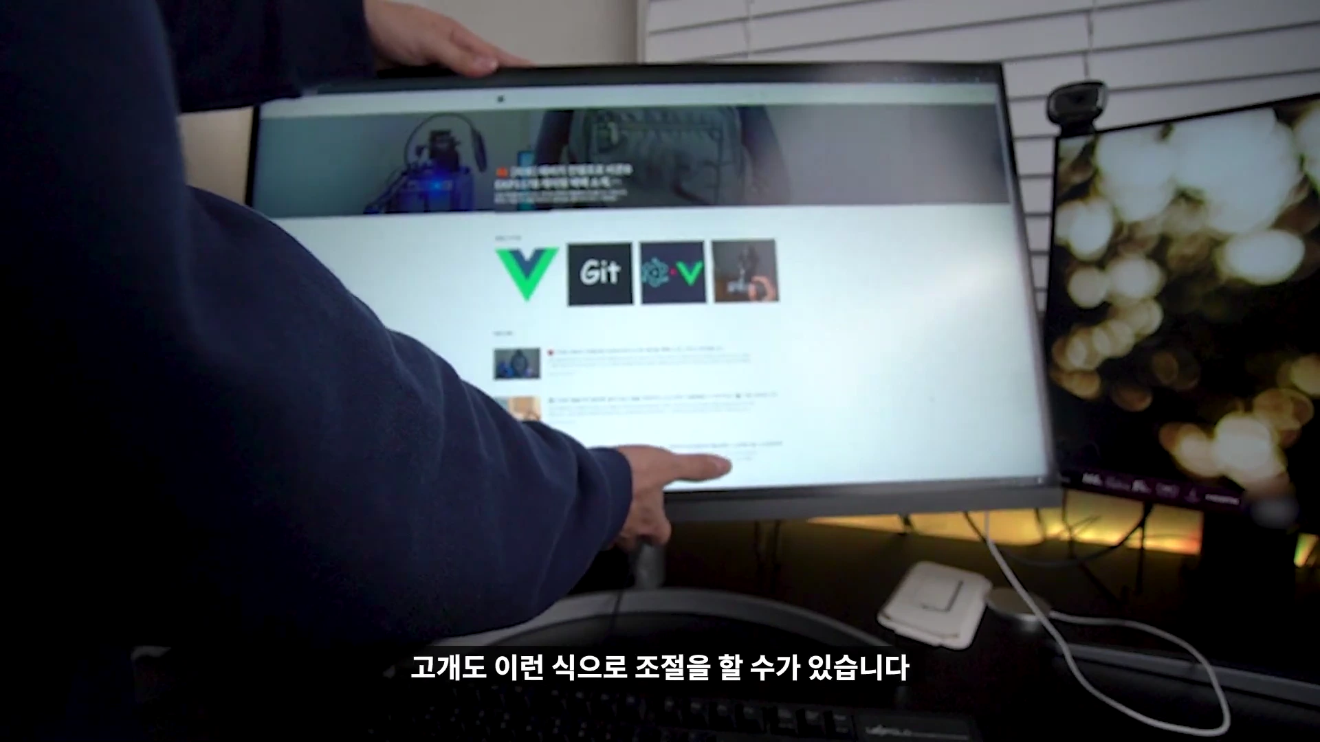 사용자가 모니터 화면 상단을 손으로 잡고 높낮이와 각도를 조절하는 모습