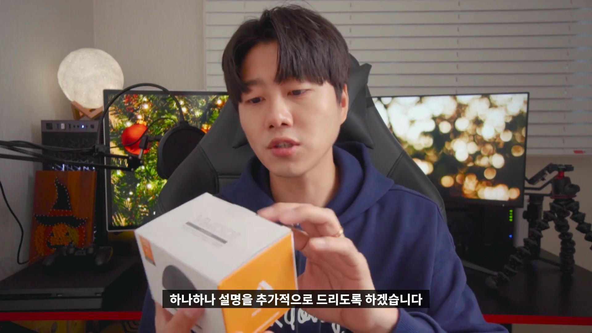 책상 앞에 앉아 에이픽스 버티컬 마우스 제품 상자를 들고 설명하는 남성