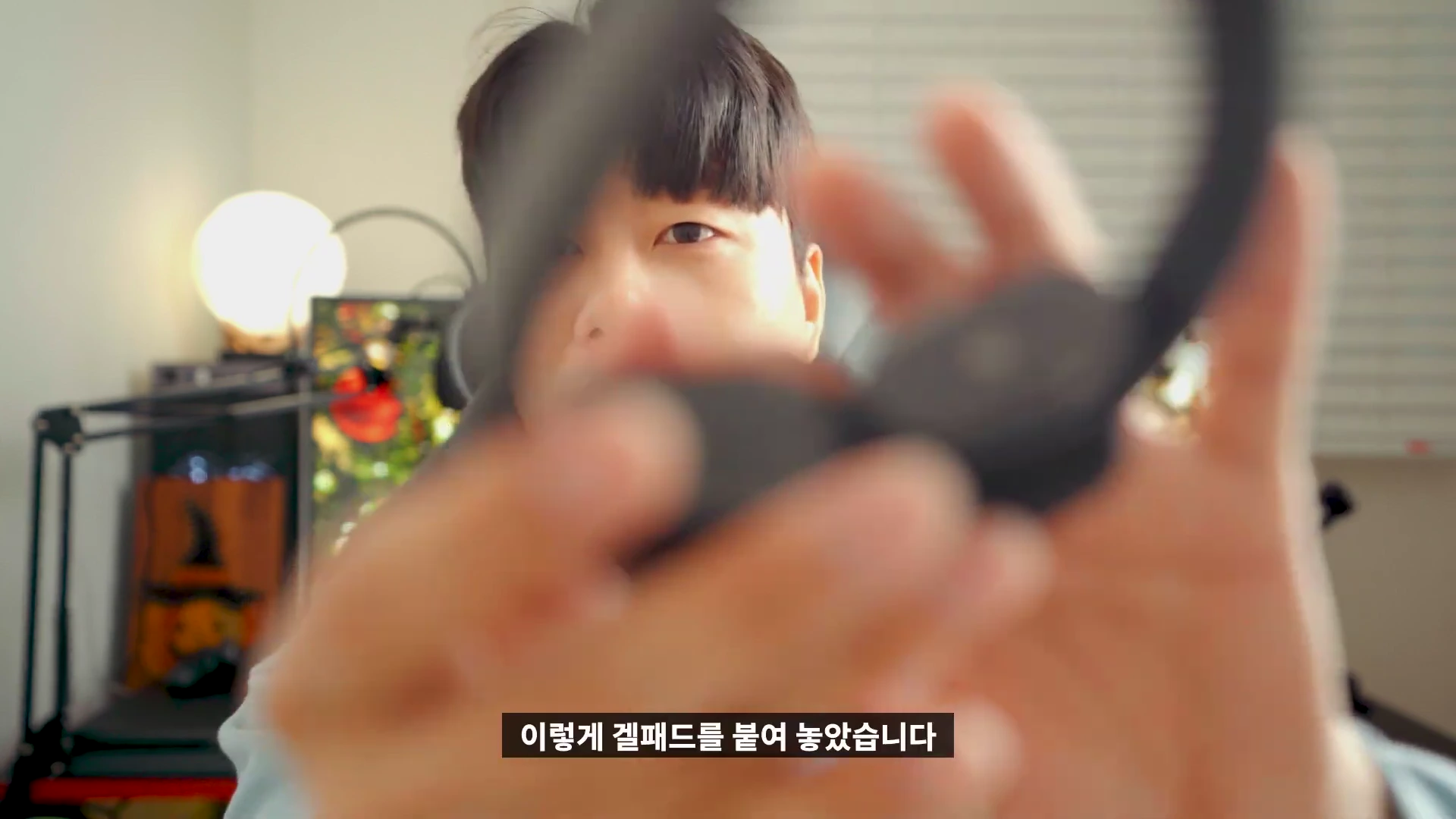 한 남성이 카메라를 향해 검은색 목 마사지기를 들어 보이고 있는 모습