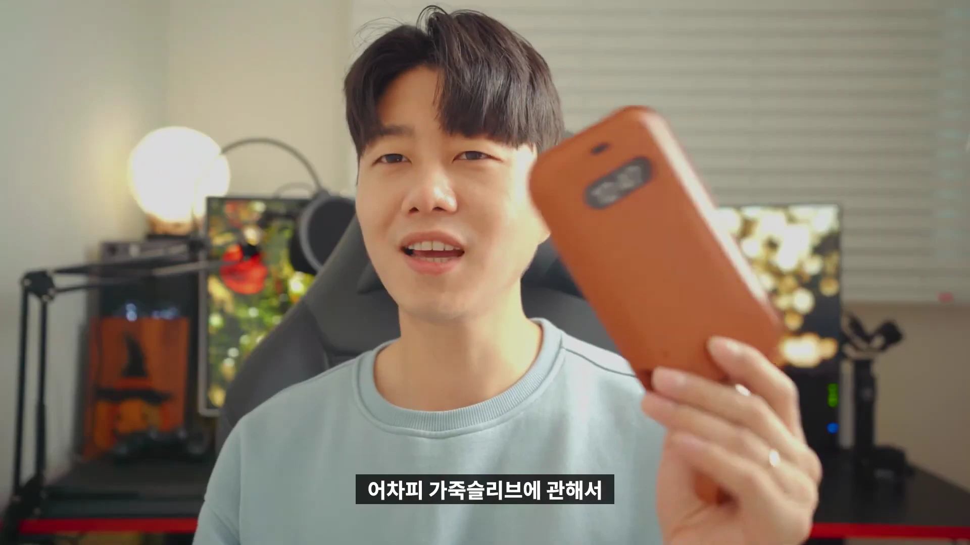 실내에서 한 남성이 갈색 가죽 슬리브를 손에 들고 설명하는 모습