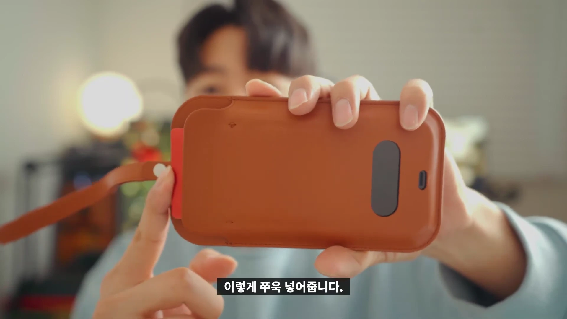 한 남성이 갈색 가죽 슬리브에 카드를 넣는 모습을 손으로 보여주고 있다.