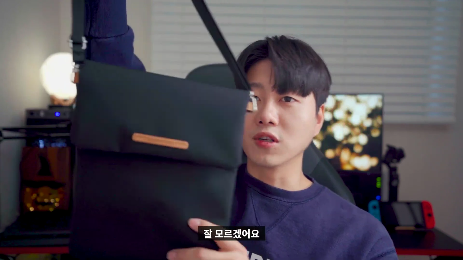 한 남성이 검은색 스타벅스 폴더블 크로스백을 들어 보이며 설명하고 있다.