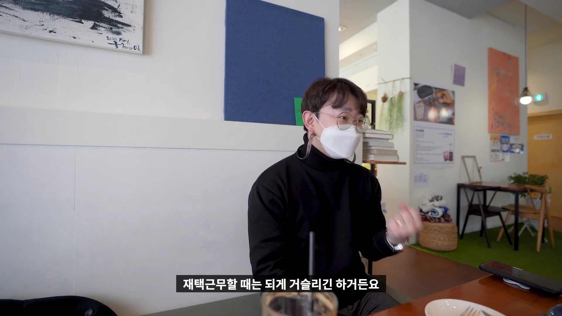 카페에 앉아 마스크를 쓴 남성이 손짓하며 이야기를 나누고 있는 모습