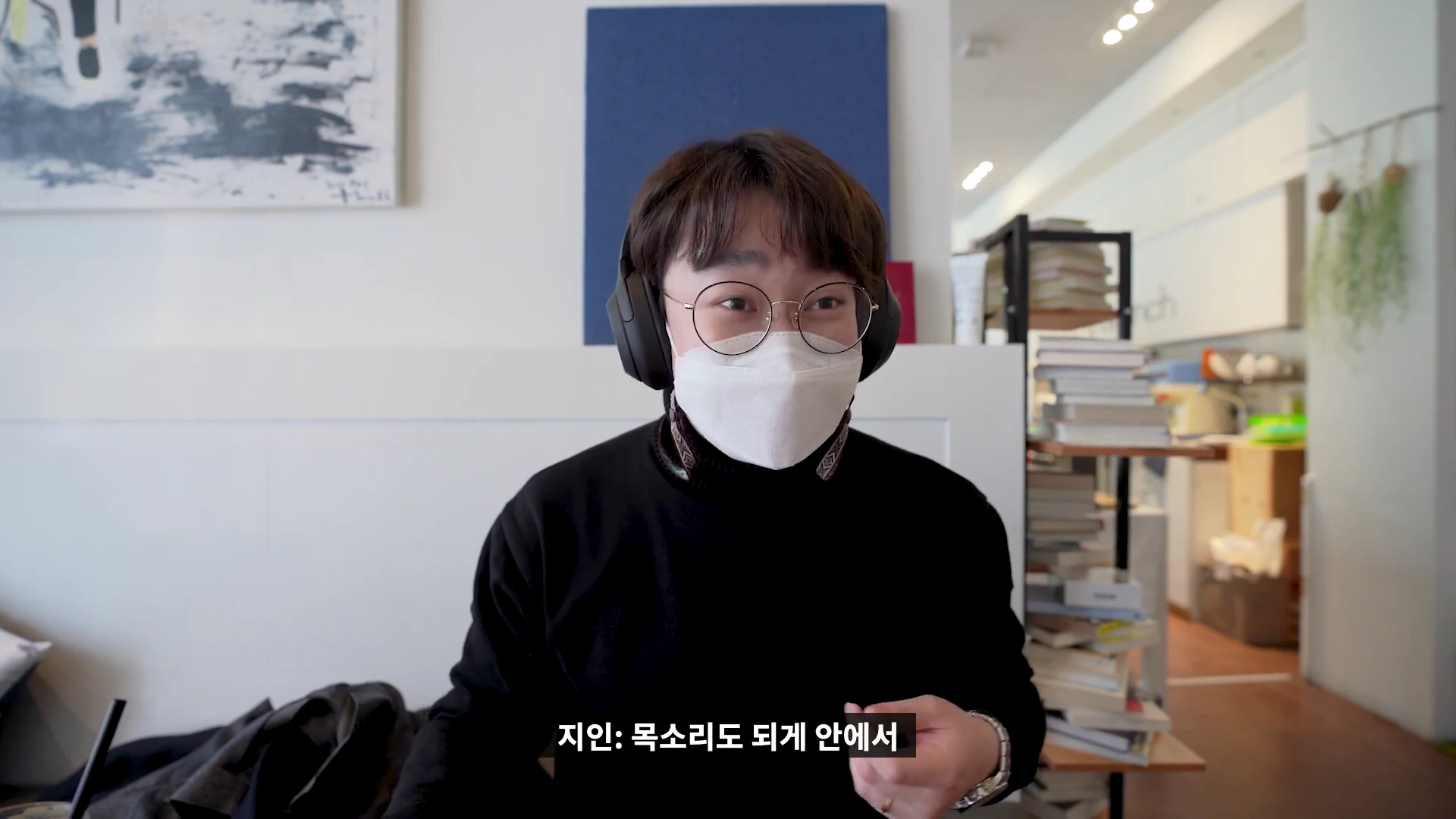 안경과 마스크를 착용한 사람이 헤드폰을 쓰고 실내에서 대화하는 모습