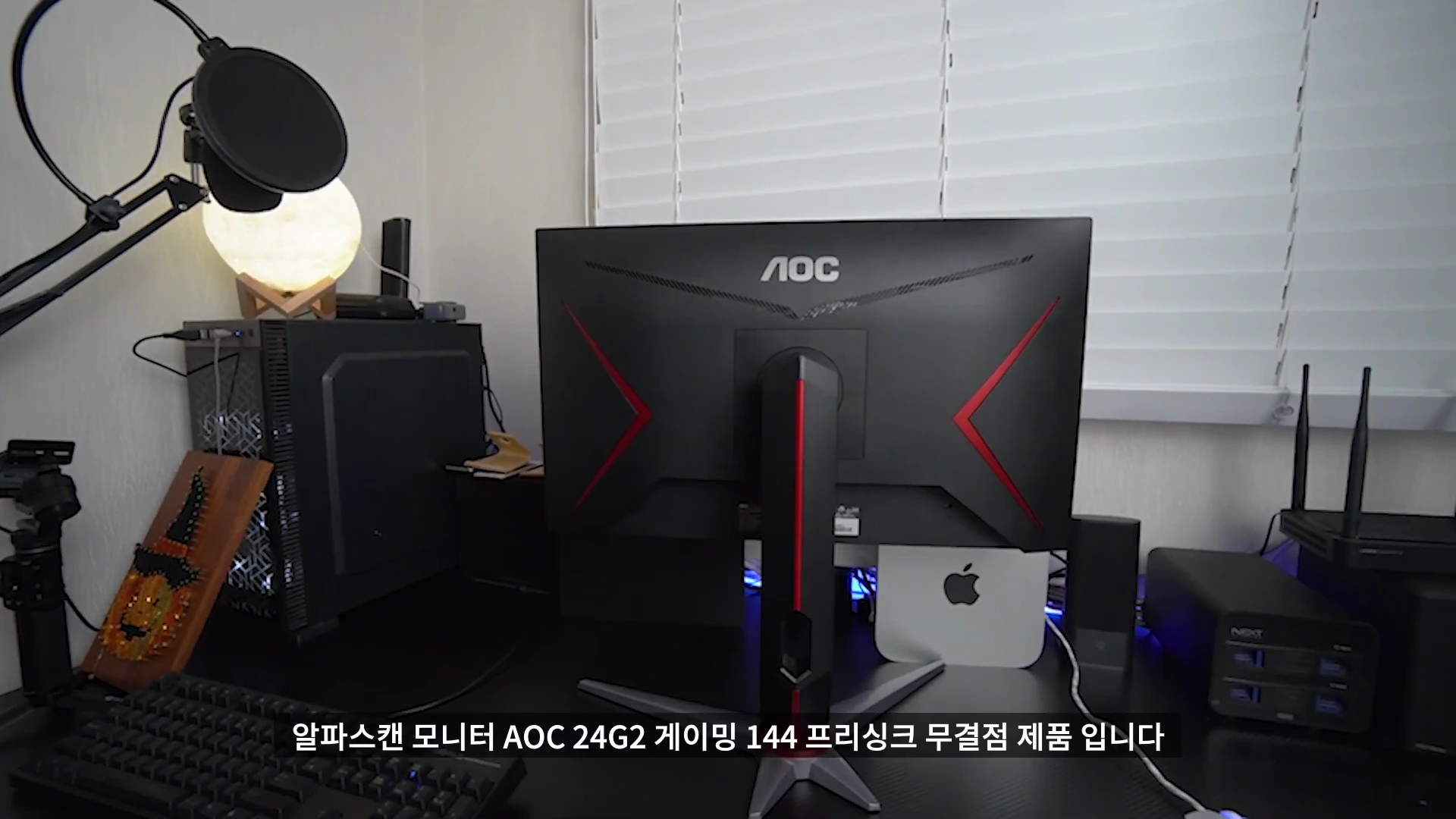 책상 위에 놓인 알파스캔 게이밍 모니터의 뒷모습과 주변 기기들