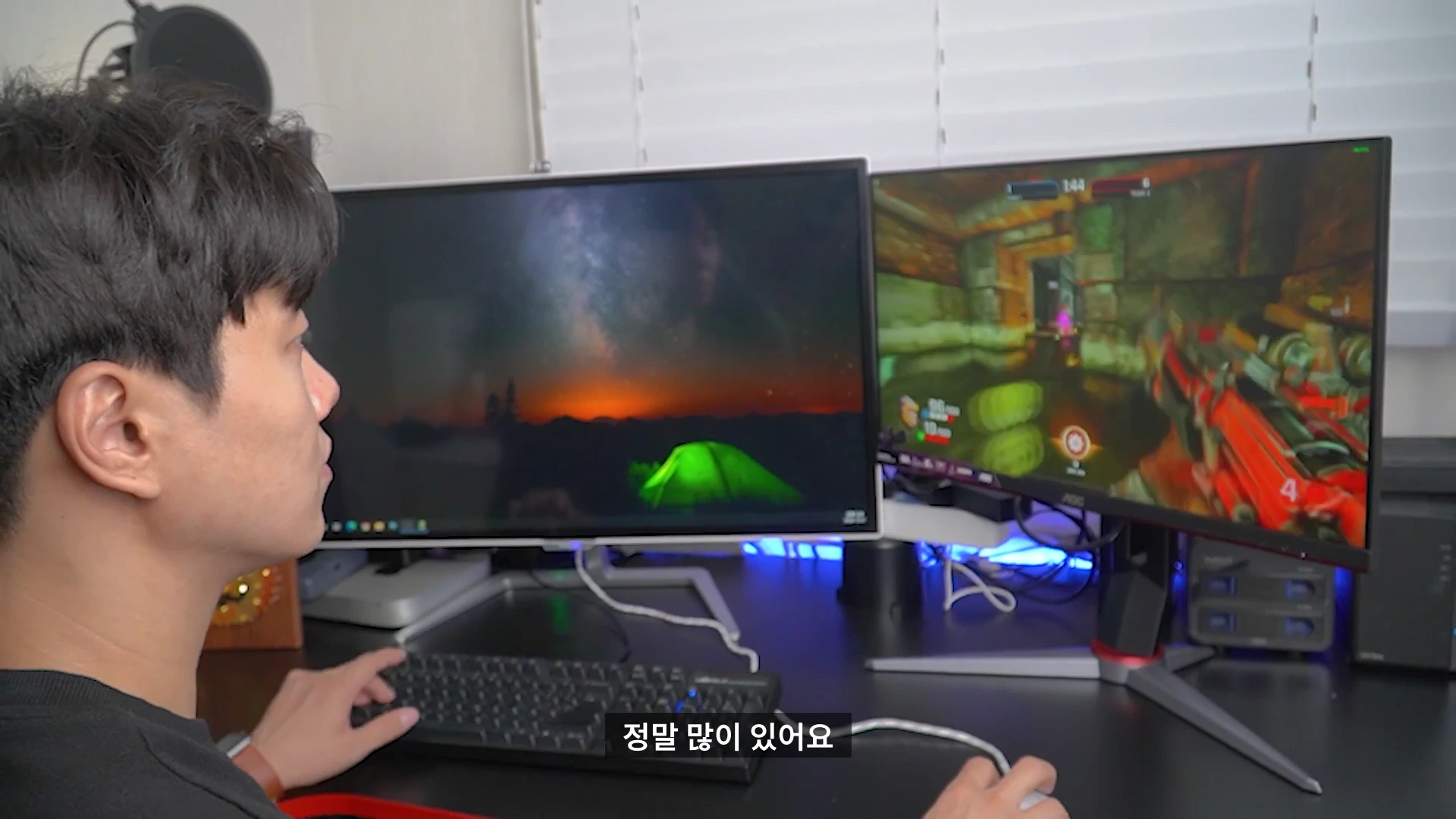책상 앞에 앉아 듀얼 모니터로 게임과 영상을 즐기는 남성의 옆모습