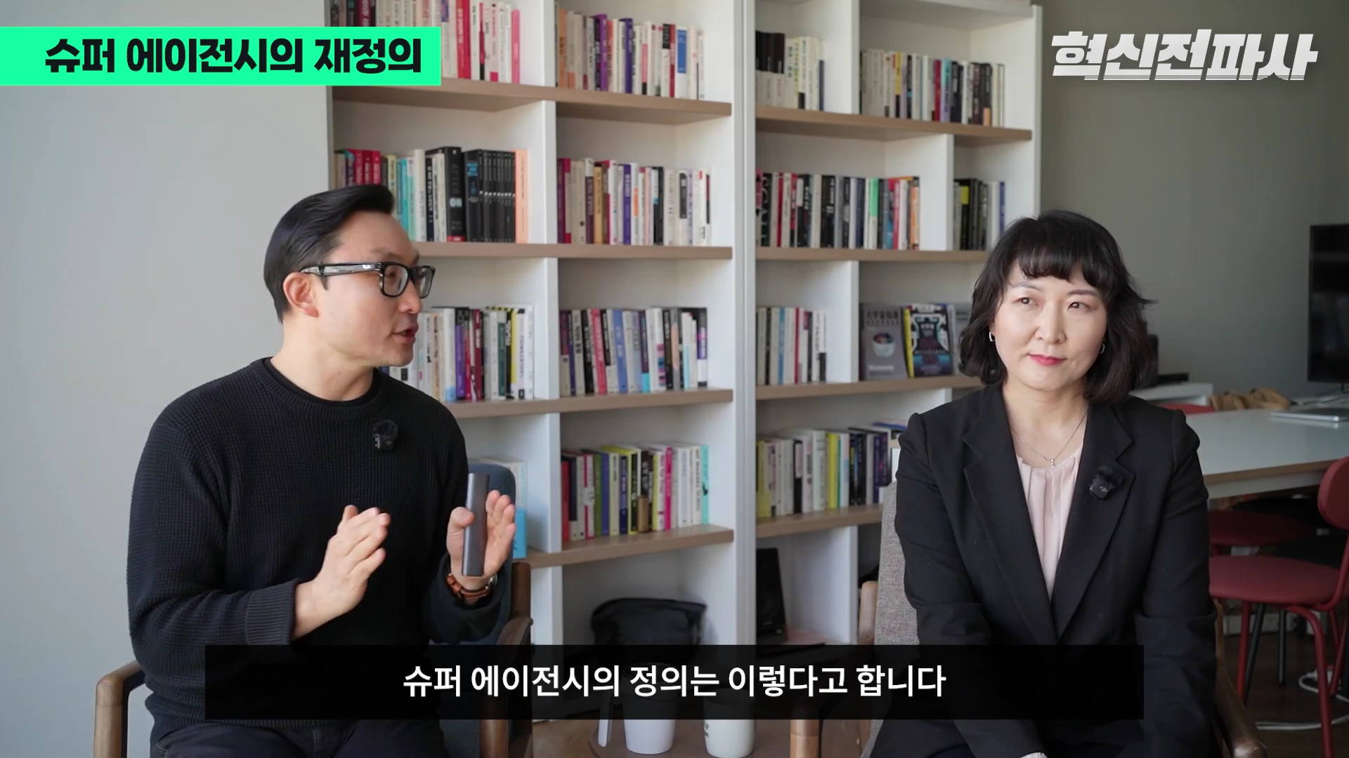 서재를 배경으로 안경을 쓴 남성과 단정한 차림의 여성이 대화를 나누는 모습