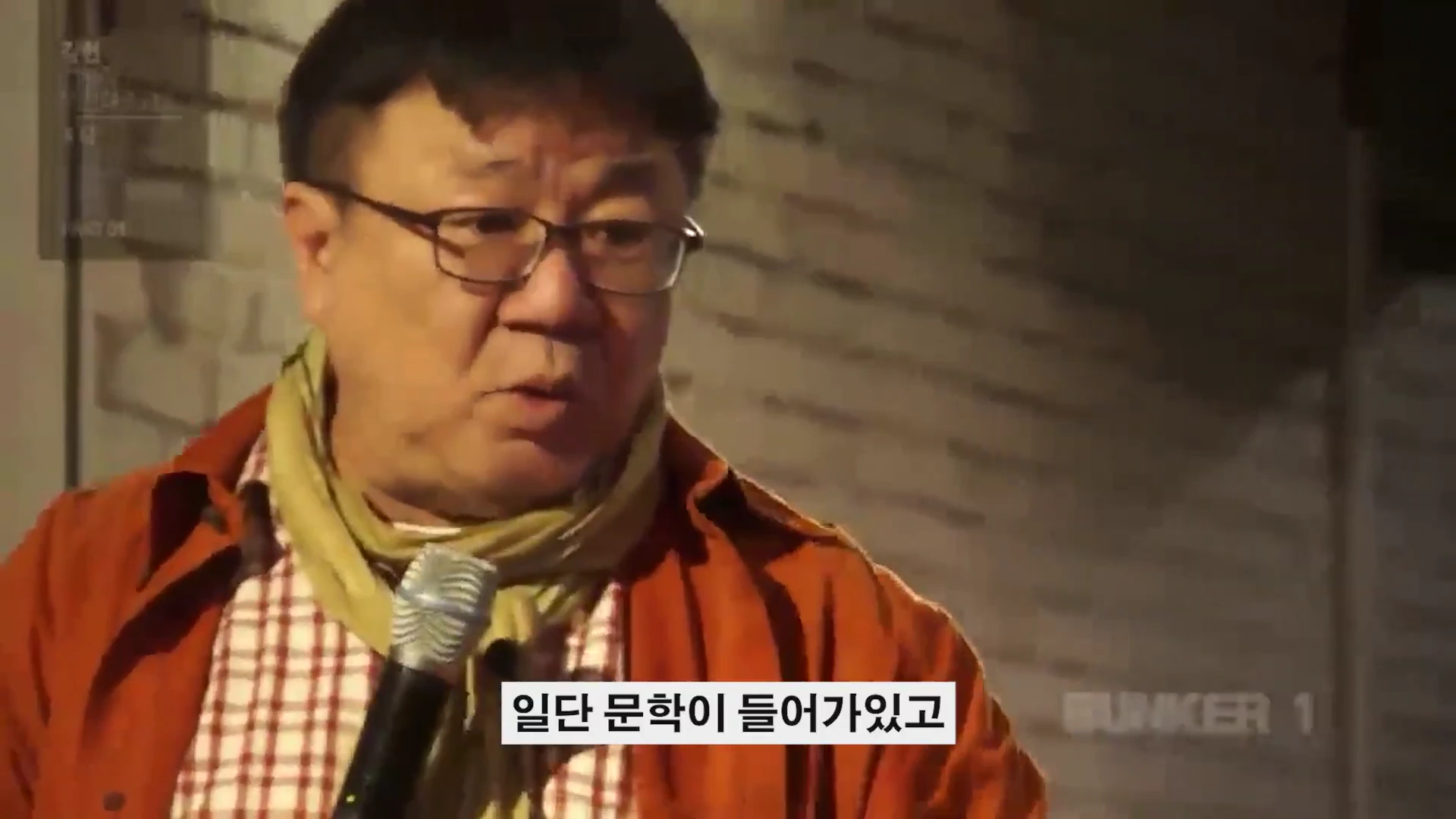 안경을 쓴 중년 남성이 마이크를 잡고 강연하는 모습