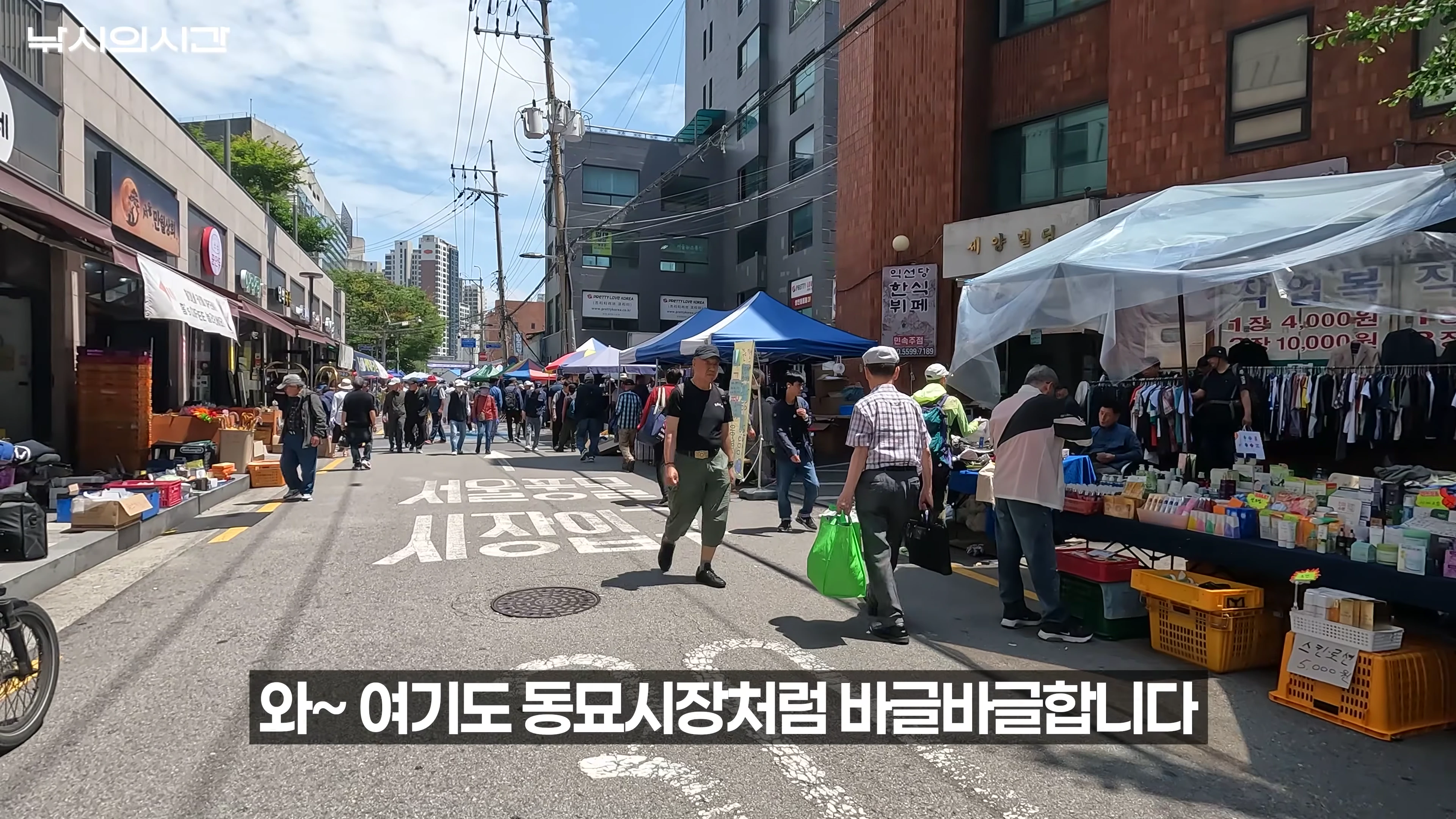 서울풍물시장 입구 거리에서 사람들이 오가며 노점을 구경하는 모습