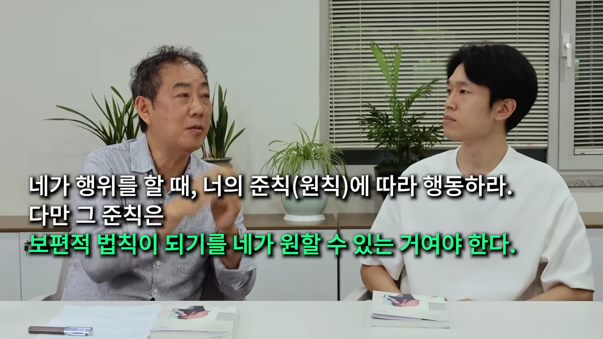 두 남성이 실내에서 대담을 나누고 있으며, 화면 중앙에 정언 명령에 관한 자막이 표시되어 있다.
