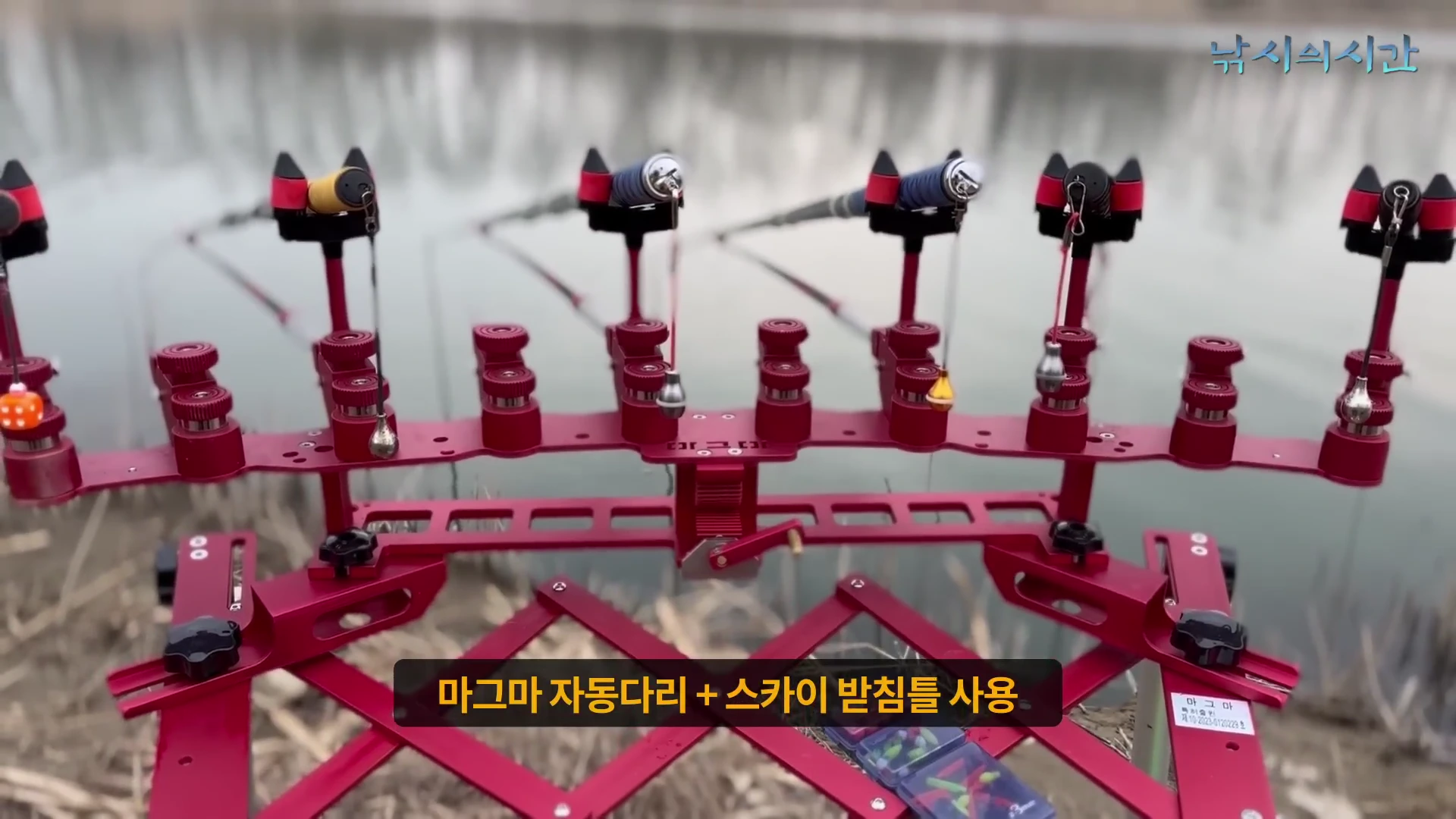 강가에 설치된 붉은색 10단 낚싯대 받침틀과 낚싯대들이 나란히 놓여 있다.