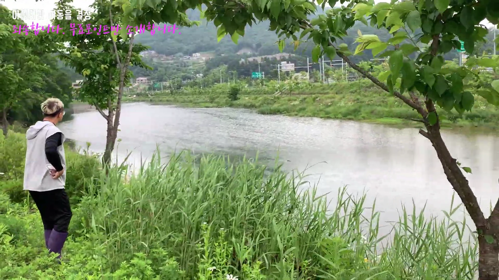 강가에 서서 물속 상황을 살피고 있는 낚시인의 뒷모습