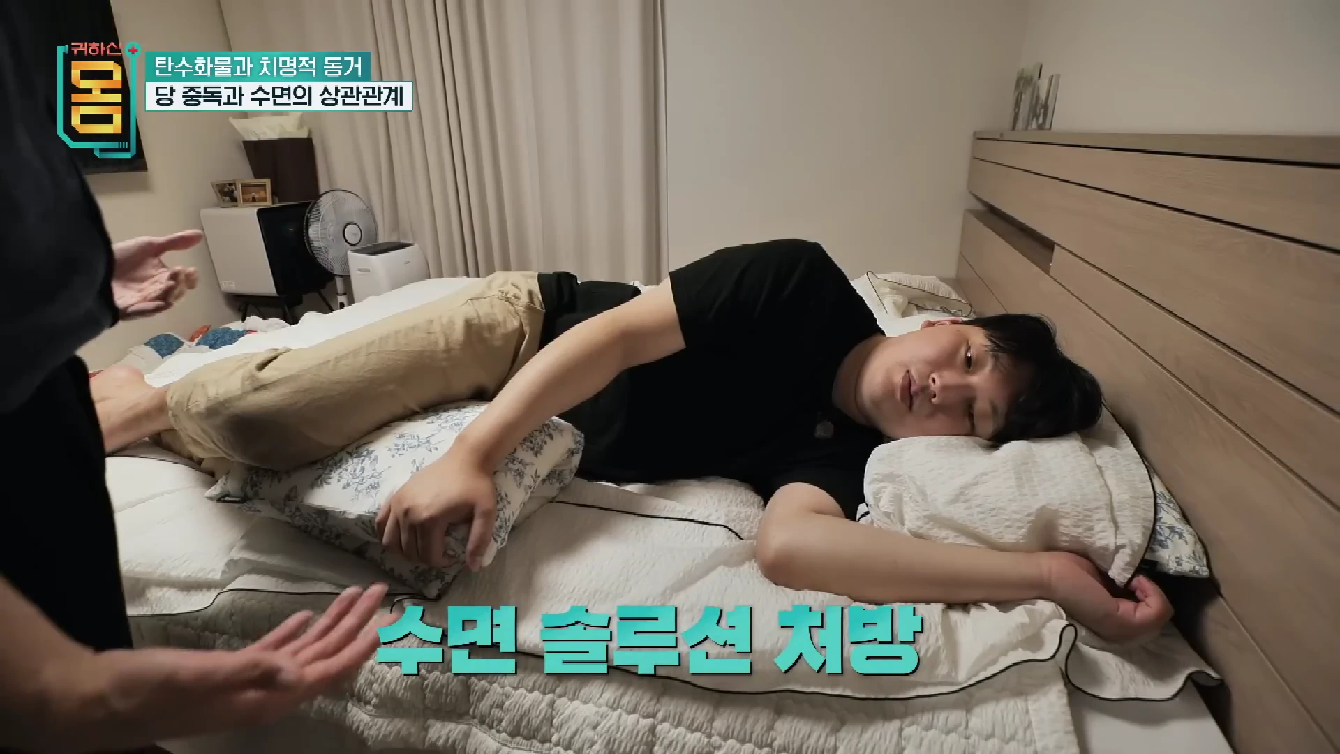 침대에 옆으로 누워 긴 베개를 안고 있는 남성과 그를 지켜보는 전문가의 모습
