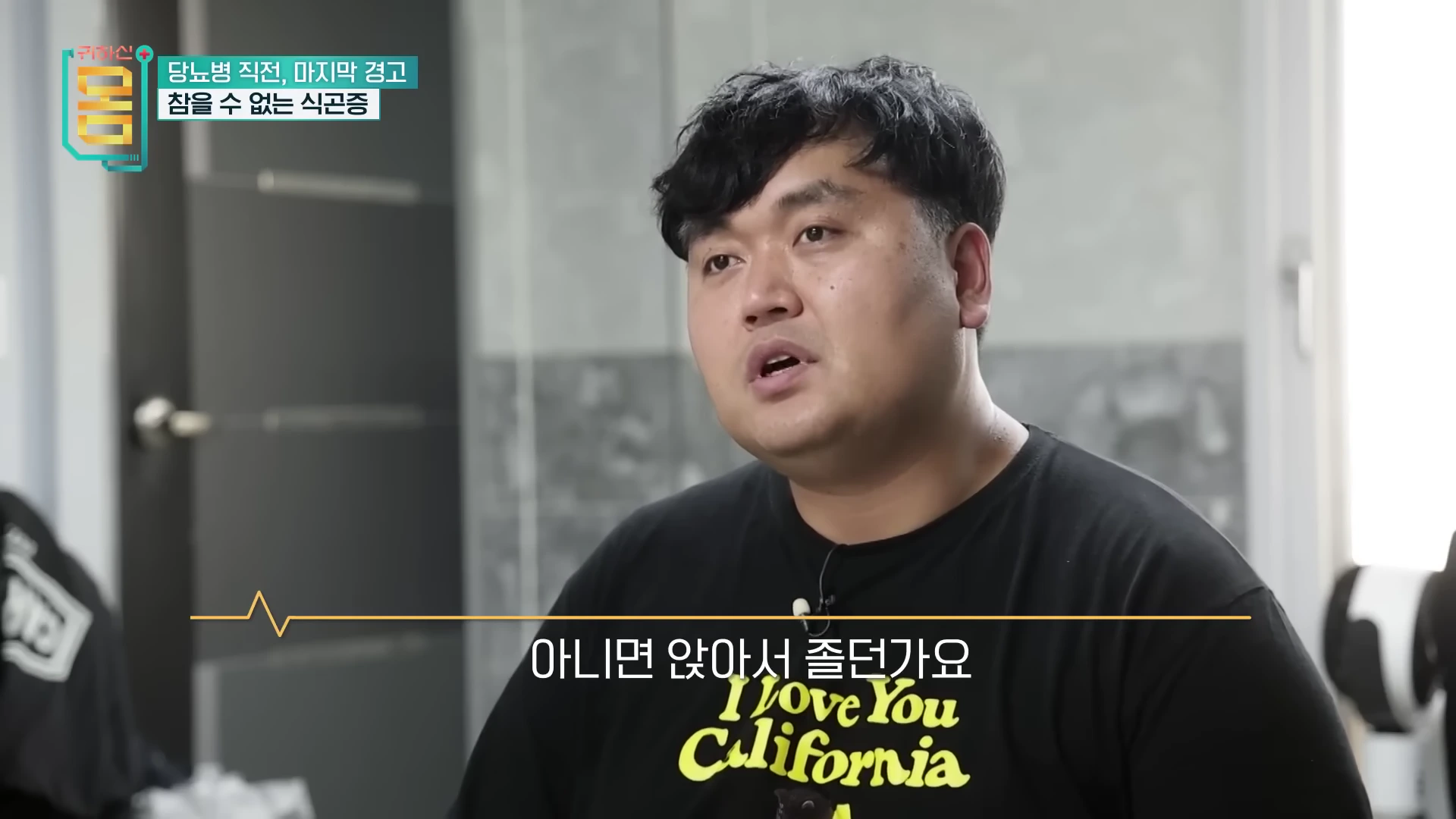 검은색 티셔츠를 입은 남성이 인터뷰 중인 모습