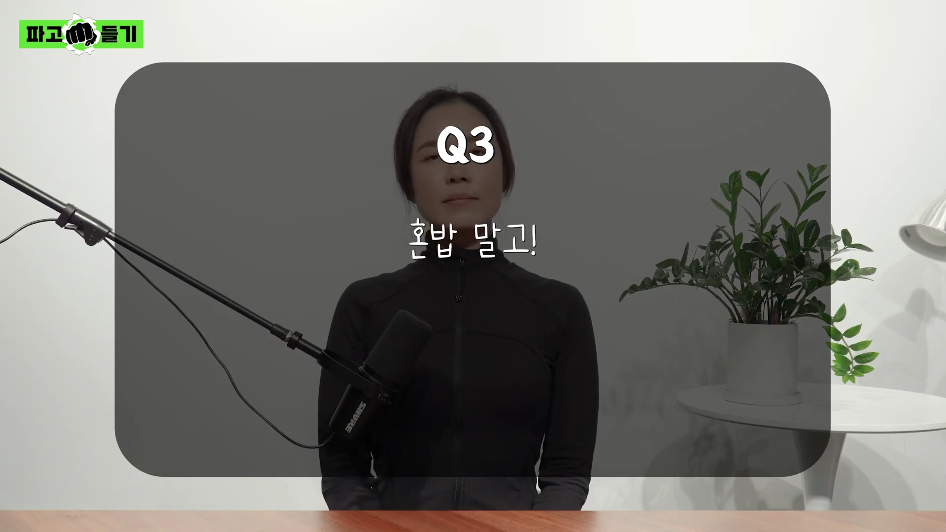 검은색 상의를 입은 여성이 마이크 앞에 앉아 있고, 화면 중앙에 'Q3 혼밥 말고!'라는 문구가 적혀 있다.