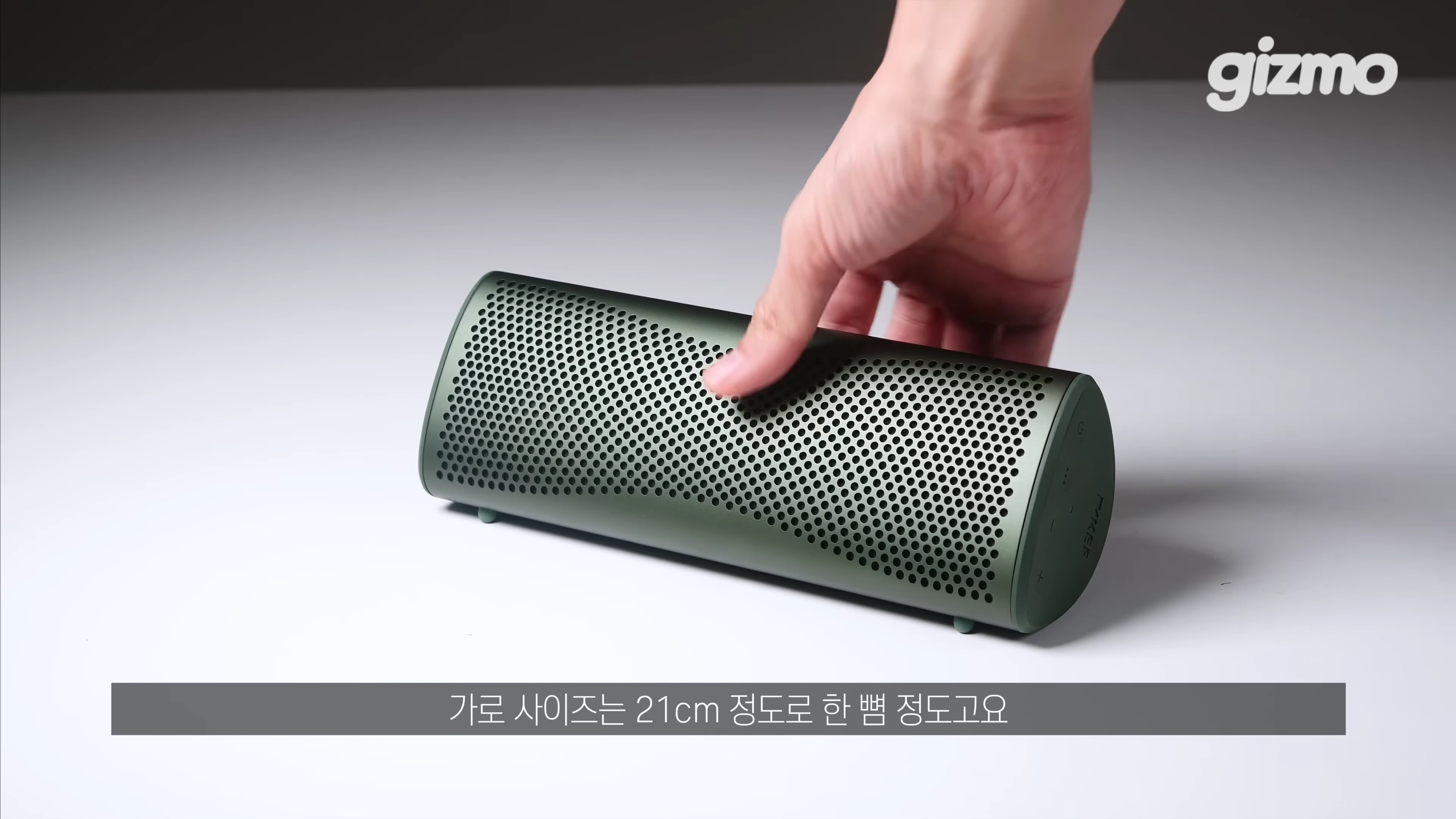 손으로 잡고 있는 올리브색 프리즘 형태의 휴대용 블루투스 스피커