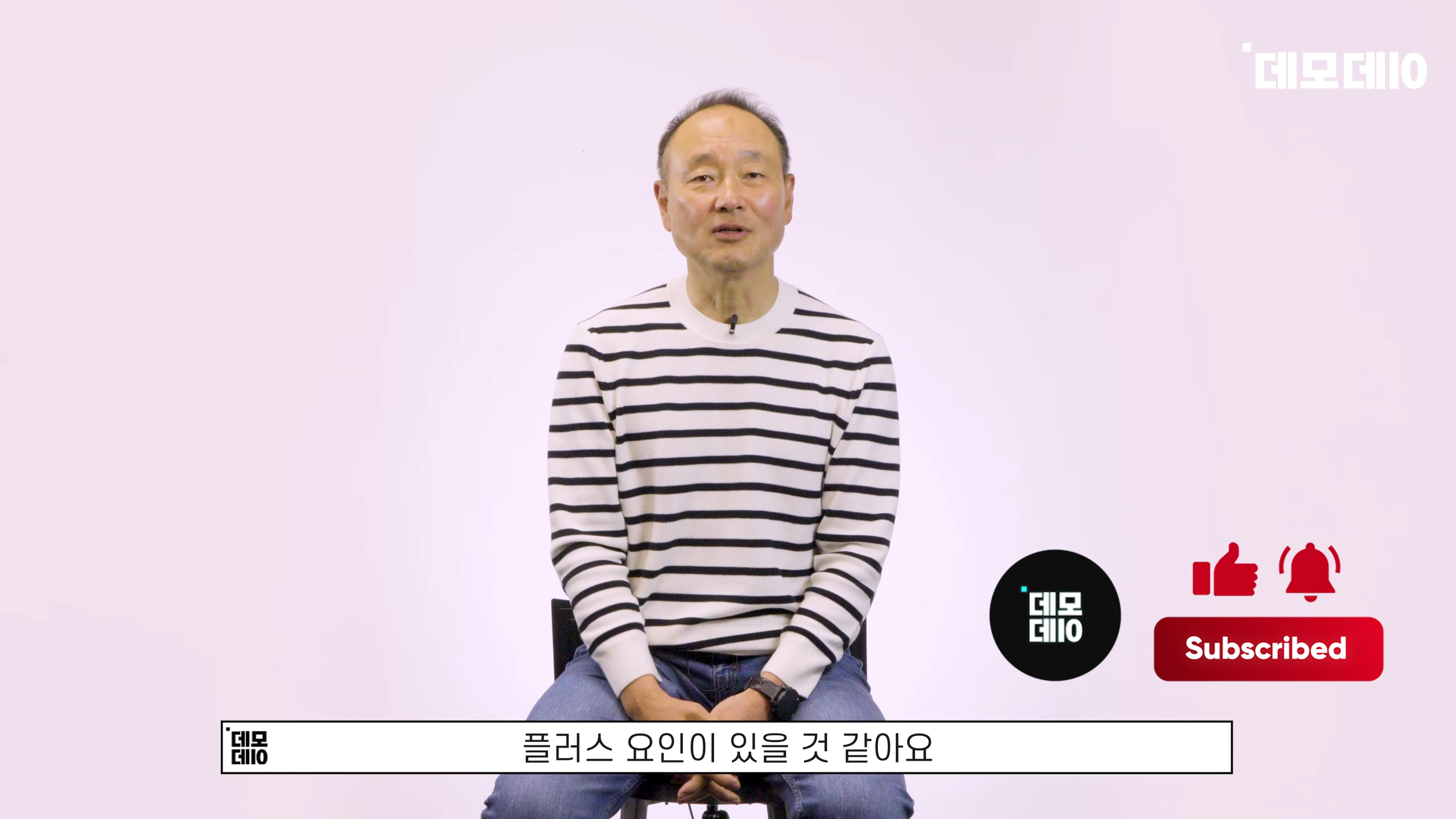 흰색 배경 앞에서 줄무늬 니트를 입은 중년 남성이 앉아 이야기하고 있다.