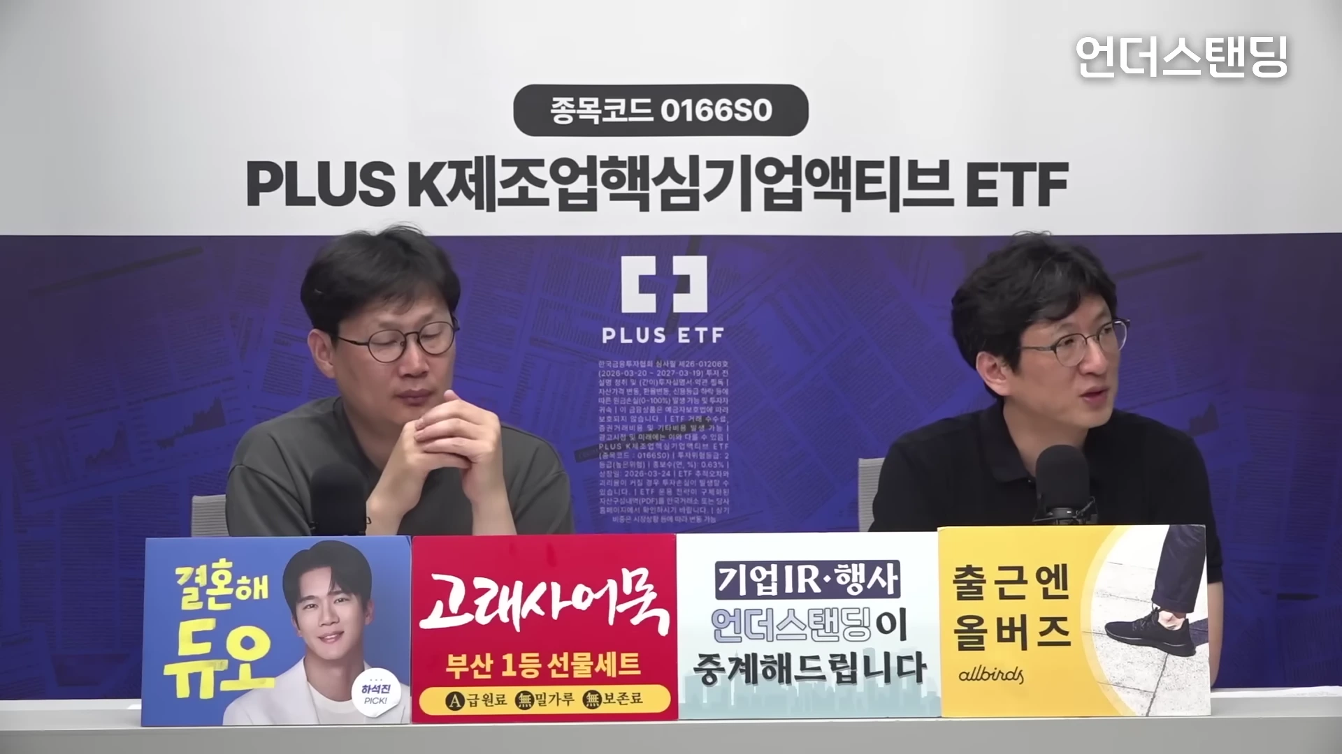 스튜디오에서 안경을 쓴 두 남성이 마이크 앞에 앉아 대화를 나누고 있으며, 앞에는 여러 광고 문구가 적힌 패널들이 놓여 있다.