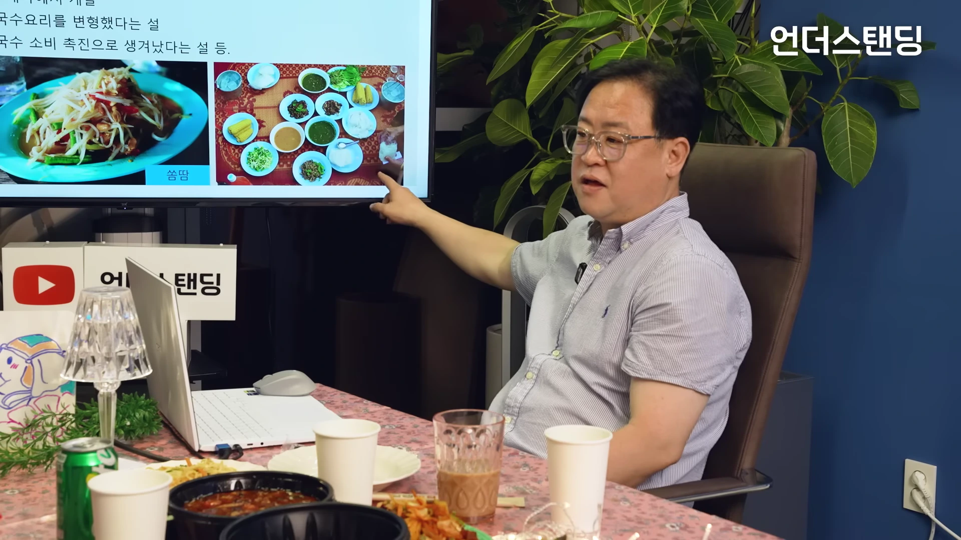 스튜디오에서 안경을 쓴 남성이 다양한 음식 사진이 담긴 화면을 손으로 가리키며 설명하고 있다.