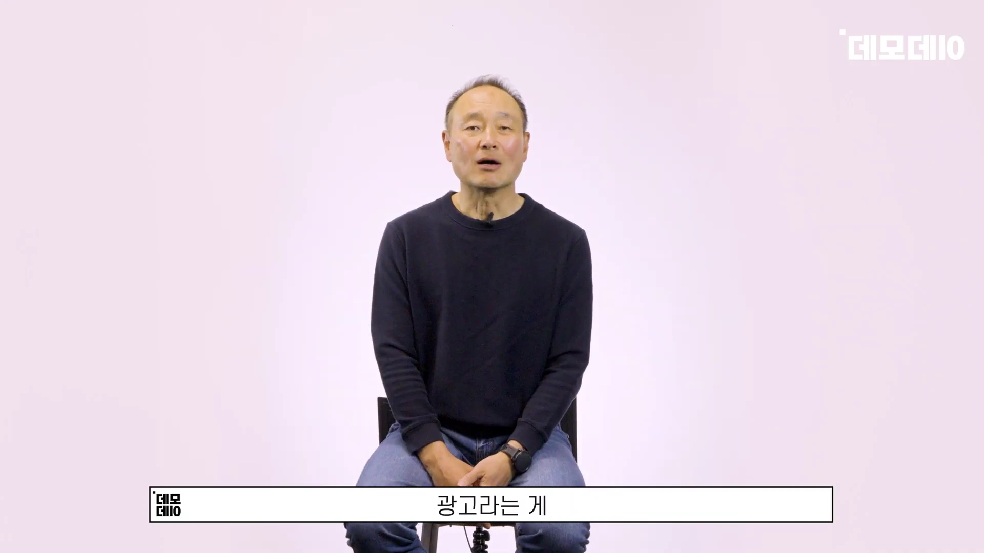 흰색 배경의 스튜디오 의자에 앉아 이야기를 나누는 중년 남성