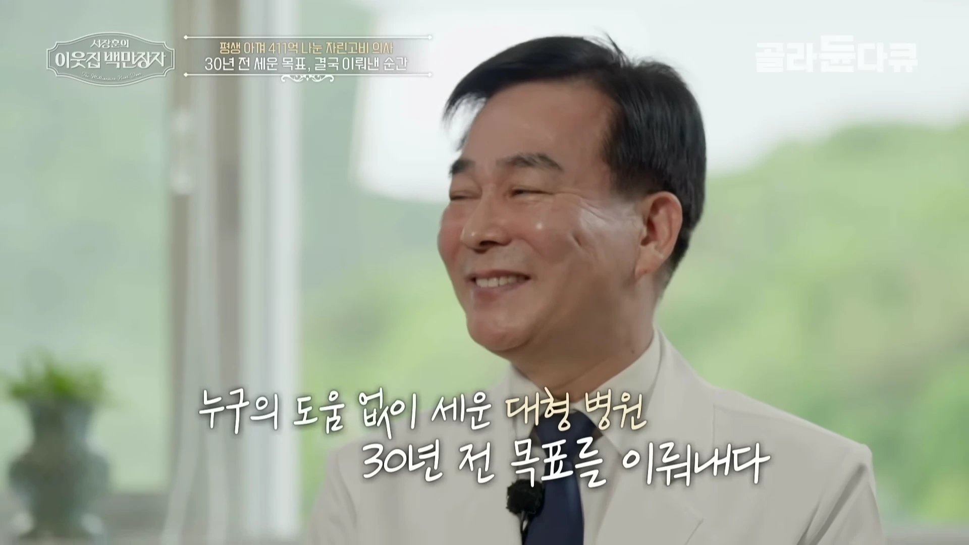 흰색 의사 가운을 입고 밝게 웃고 있는 중년 남성의 모습이 담긴 방송 화면