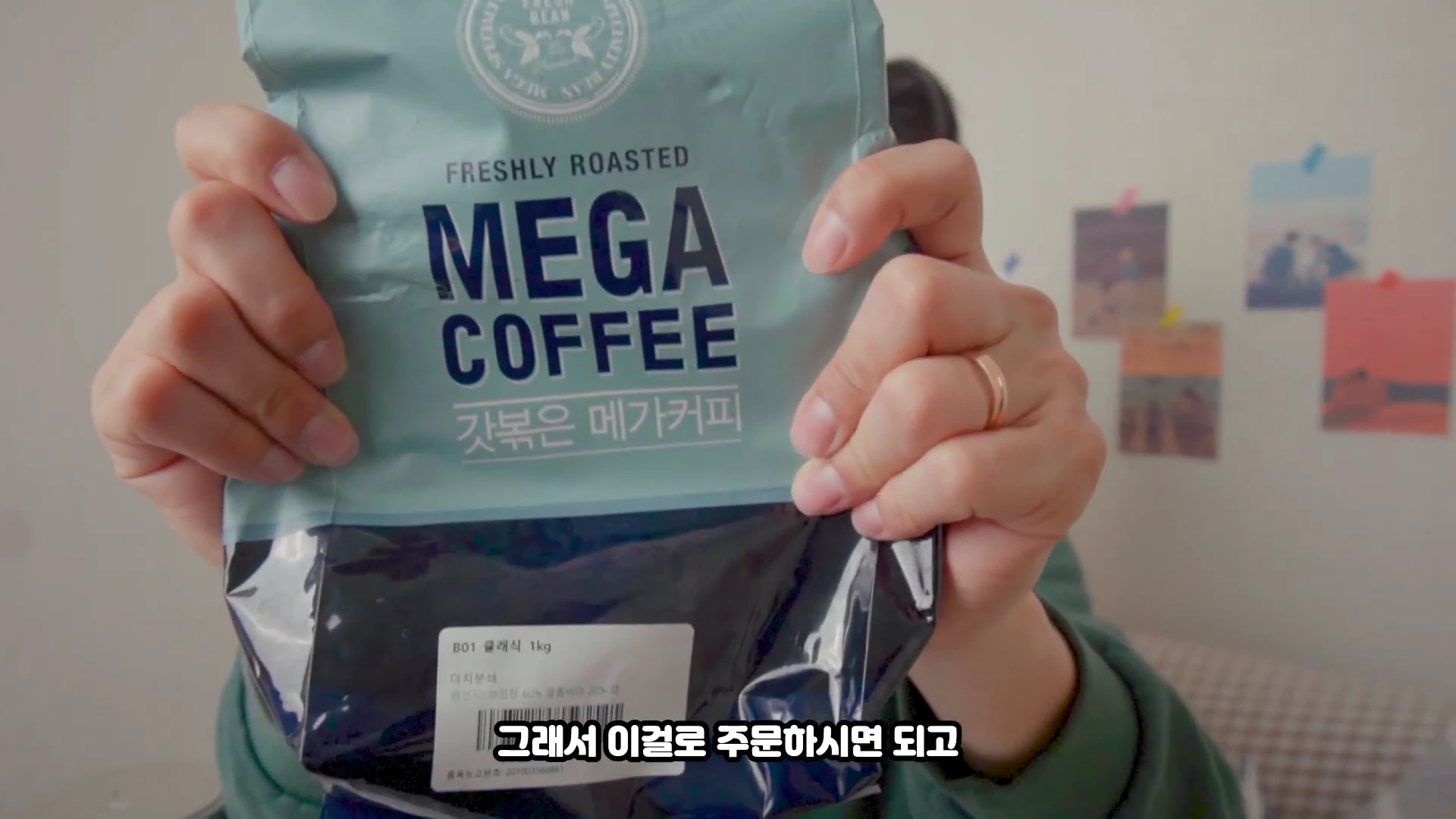 한 사람이 메가커피 원두 패키지를 양손으로 들어 보여주고 있다.