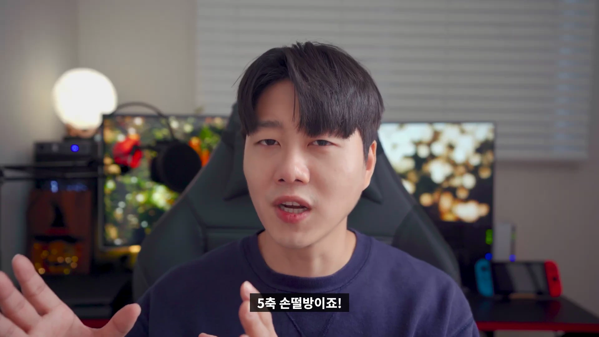 실내에서 카메라를 보며 이야기하는 남성, 화면 하단에 '5축 손떨방이죠!'라는 자막이 표시됨