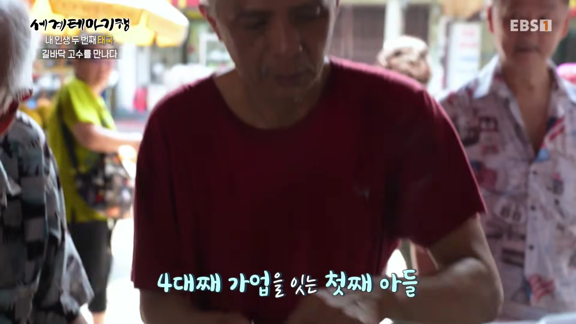 붉은색 티셔츠를 입은 중년 남성이 길거리에서 음식을 만들고 있는 모습