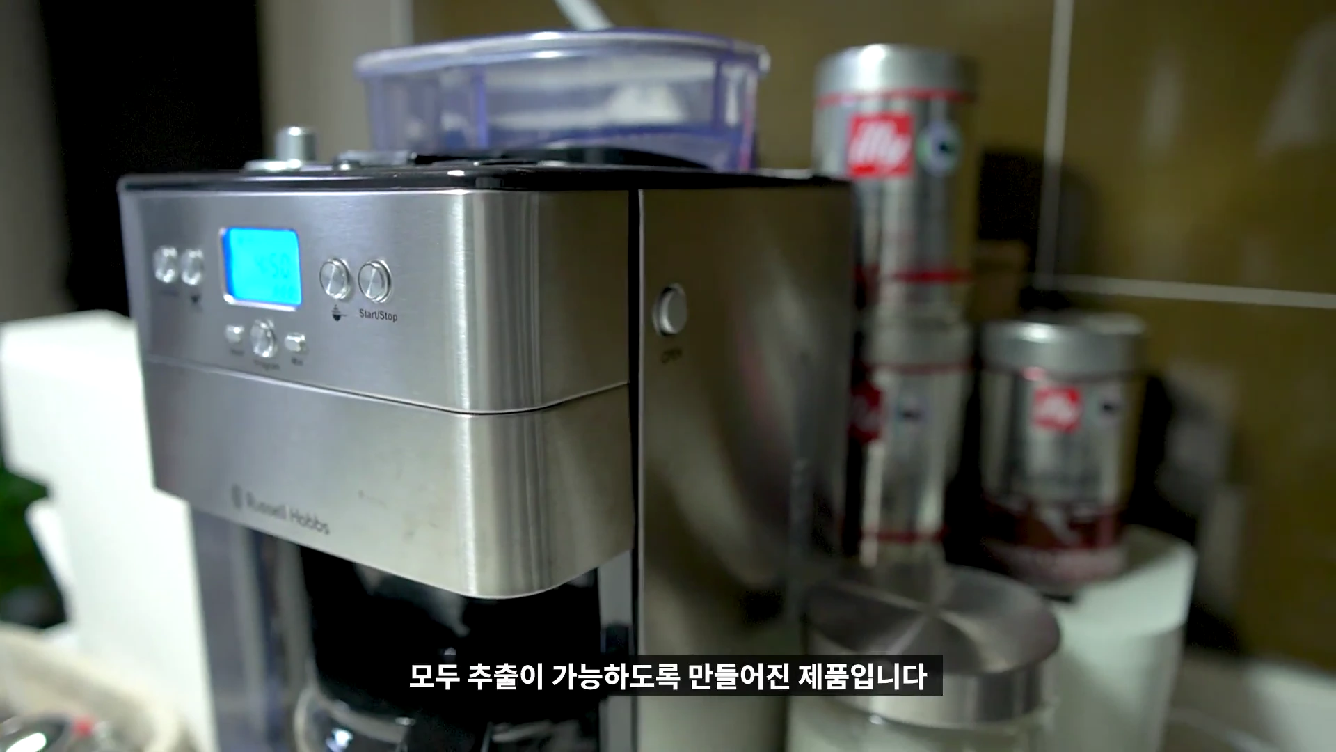 스테인리스 재질의 러셀홉스 커피머신 전면부와 조작 버튼, 디스플레이 화면