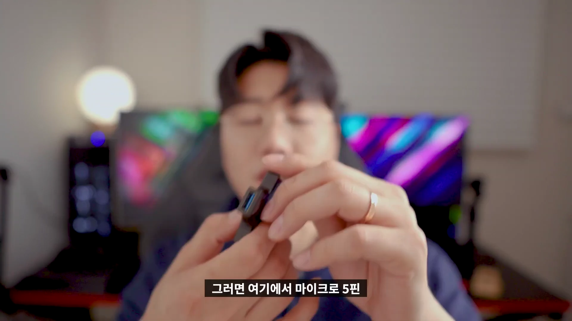 한 남성이 손에 작은 USB 테스터기를 들고 제품의 포트 구성을 보여주고 있는 모습