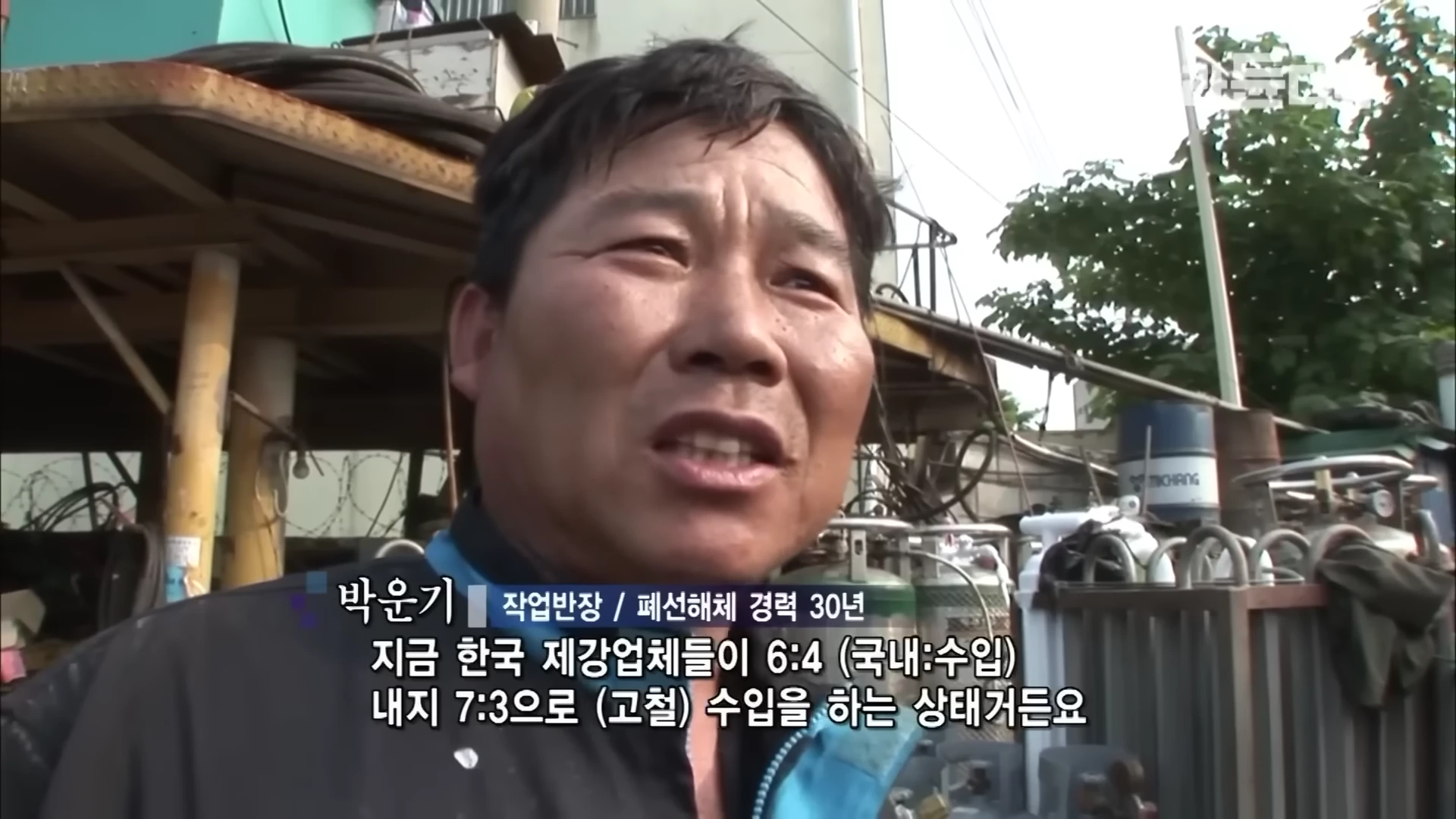 작업복을 입은 중년 남성이 야외 작업장에서 인터뷰하는 모습