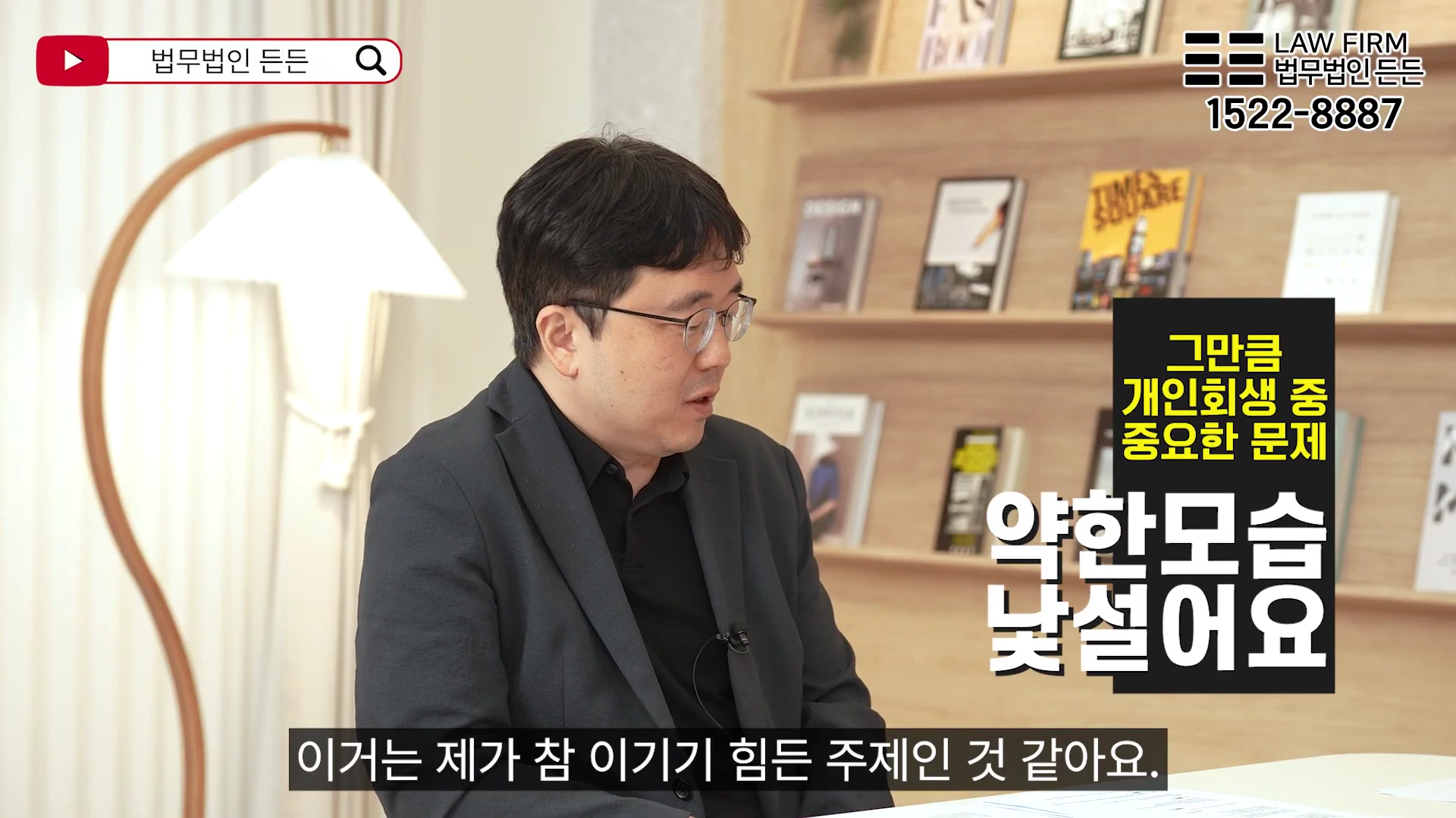 안경을 쓴 남성 변호사가 서재를 배경으로 앉아 진지하게 대화를 나누고 있는 모습