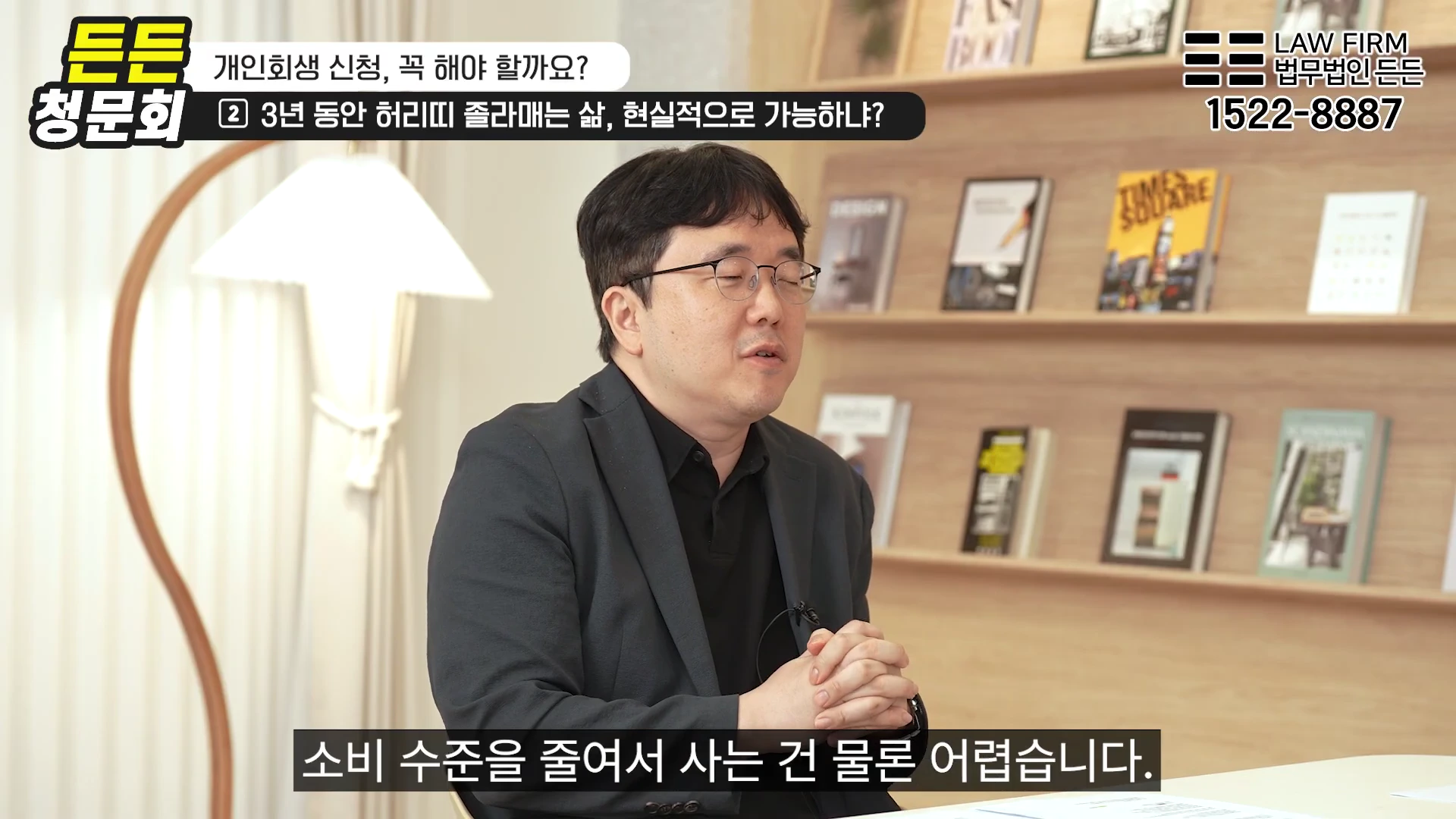 안경을 쓴 남성이 사무실 배경에서 진지한 표정으로 인터뷰에 응하고 있으며, 화면 상단에는 개인회생 관련 자막이 표시되어 있습니다.