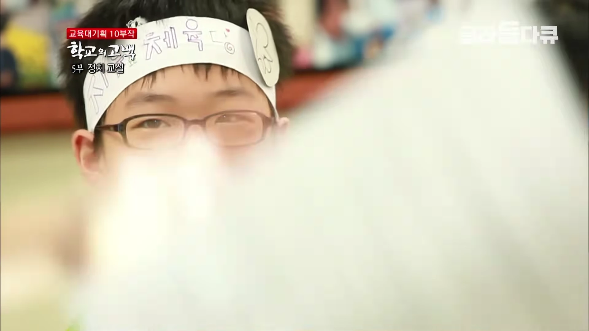 안경을 쓴 학생이 '체육당'이라고 적힌 머리띠를 두르고 정면을 응시하고 있다.