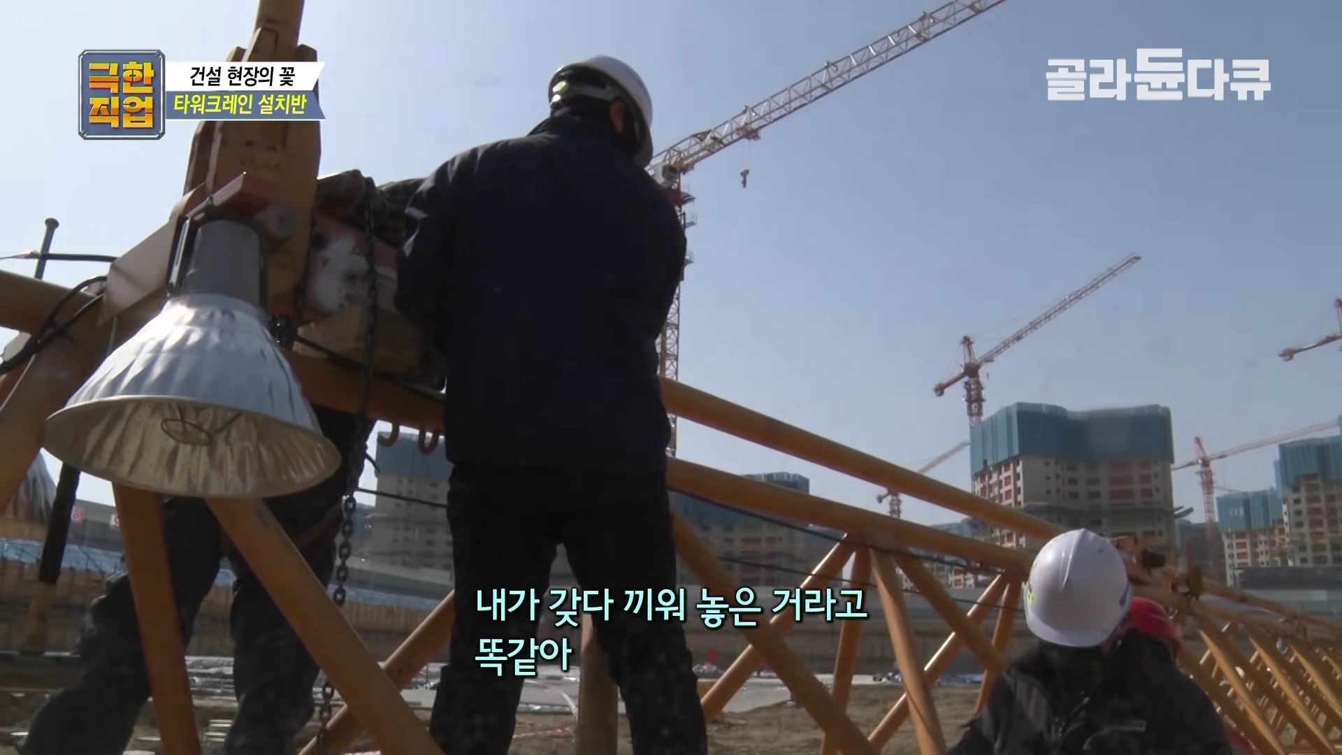 건설 현장에서 안전모를 쓴 작업자들이 타워크레인의 철제 구조물을 조립하고 있는 모습