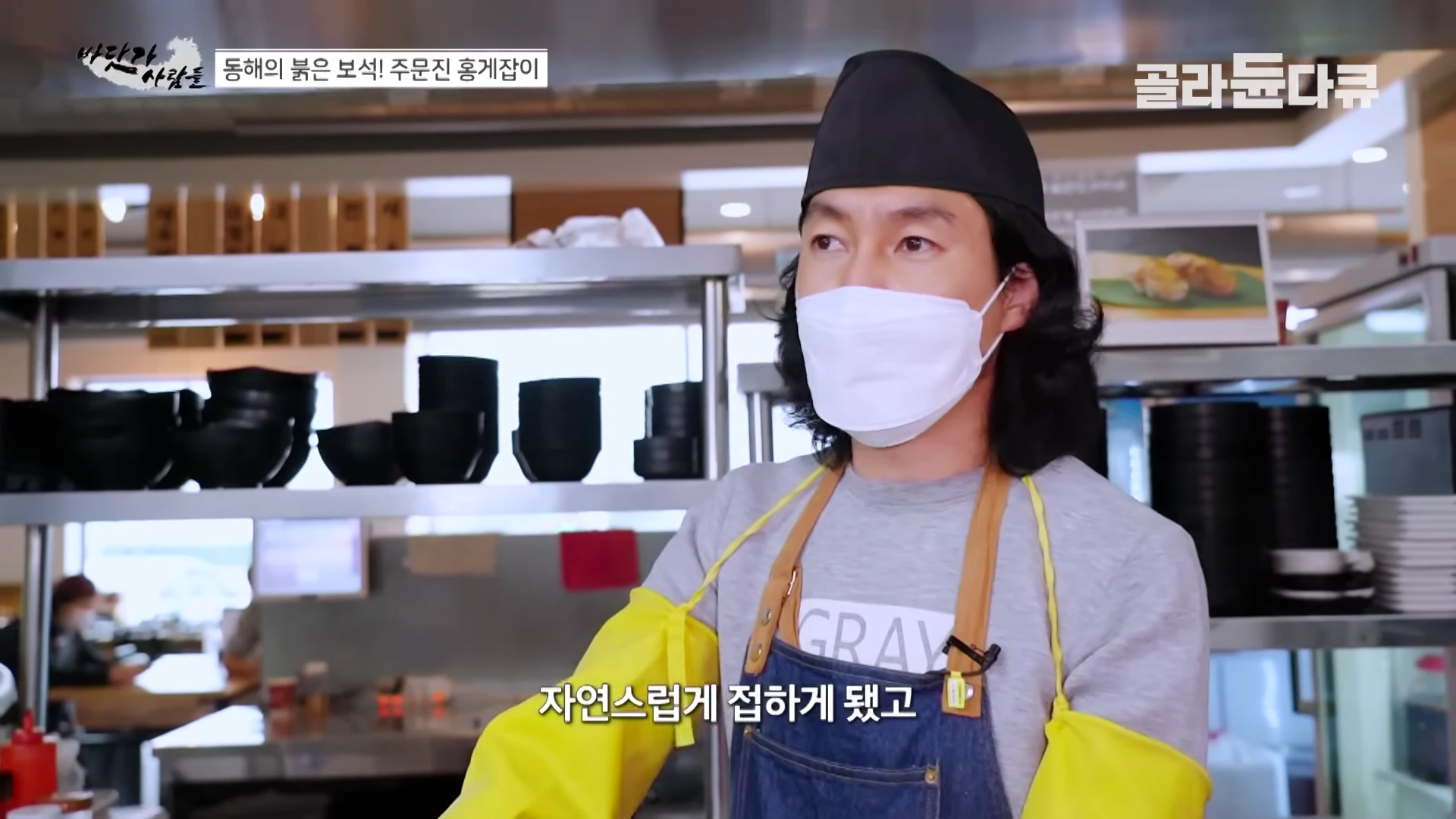 검은색 모자와 마스크를 착용한 요리사가 주방에서 인터뷰하고 있는 모습