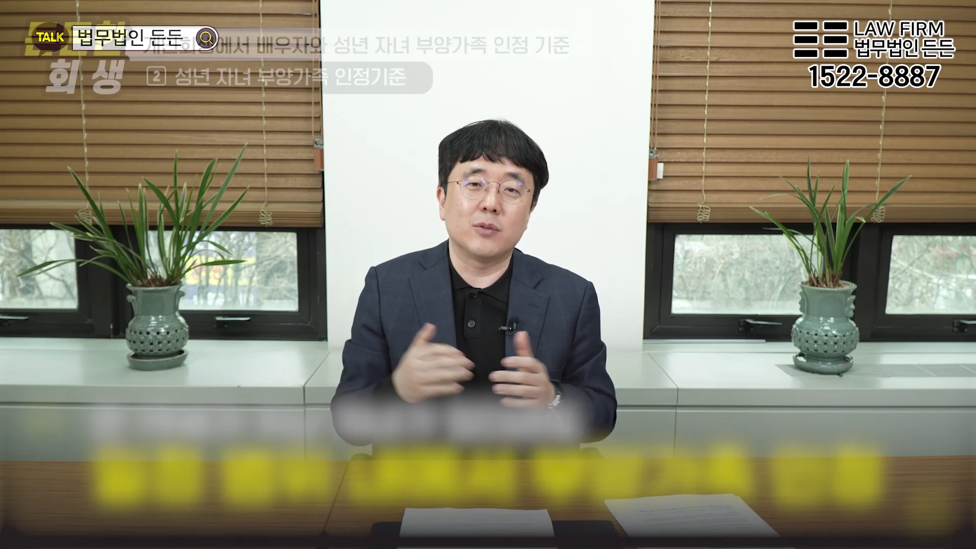 안경을 쓴 남성이 사무실 책상에 앉아 개인회생 관련 정보를 설명하고 있는 모습