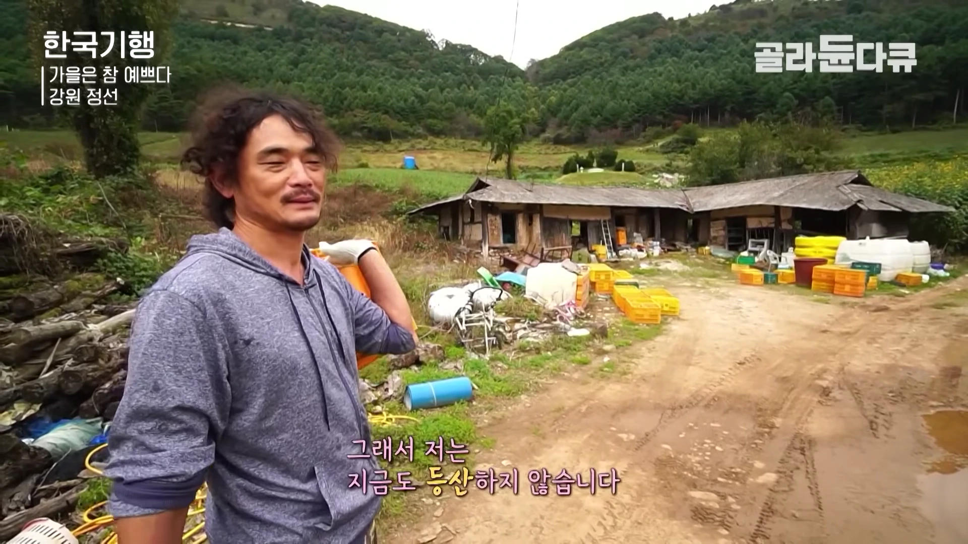 강원도 정선의 시골 마을을 배경으로 회색 후드티를 입은 남성이 서 있고, 화면 하단에는 자막이 표시되어 있다.