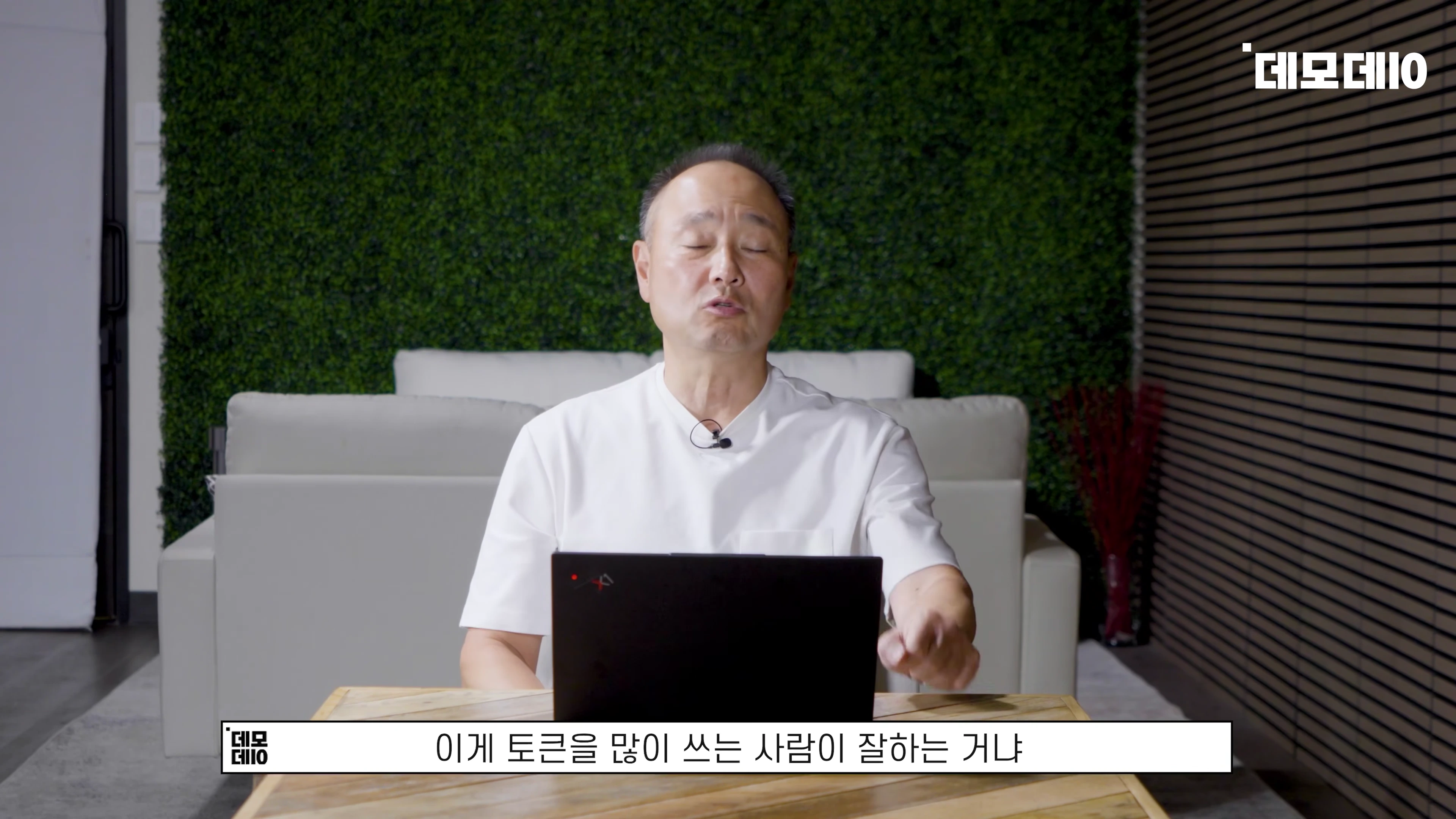 흰색 티셔츠를 입은 중년 남성이 노트북 앞에 앉아 이야기를 나누고 있는 모습