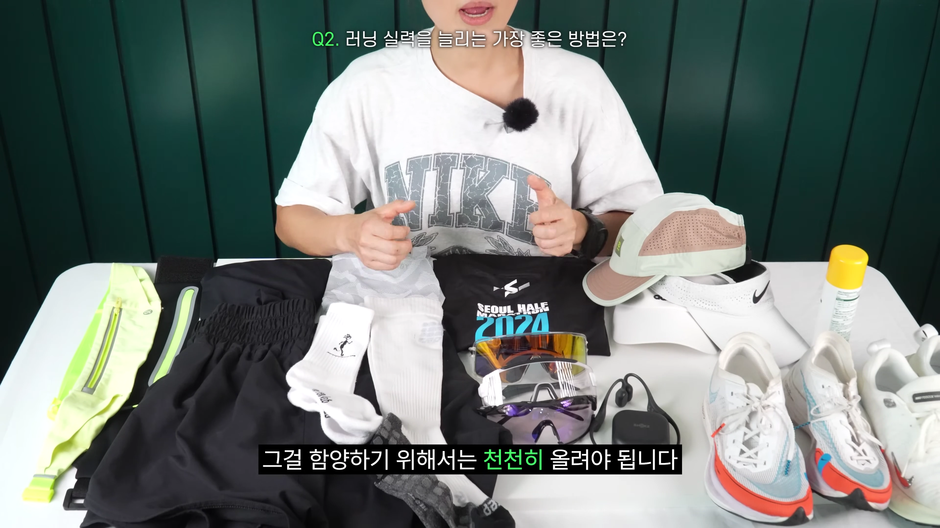 러닝 용품들이 놓인 테이블 앞에 앉아 설명하는 사람의 상반신