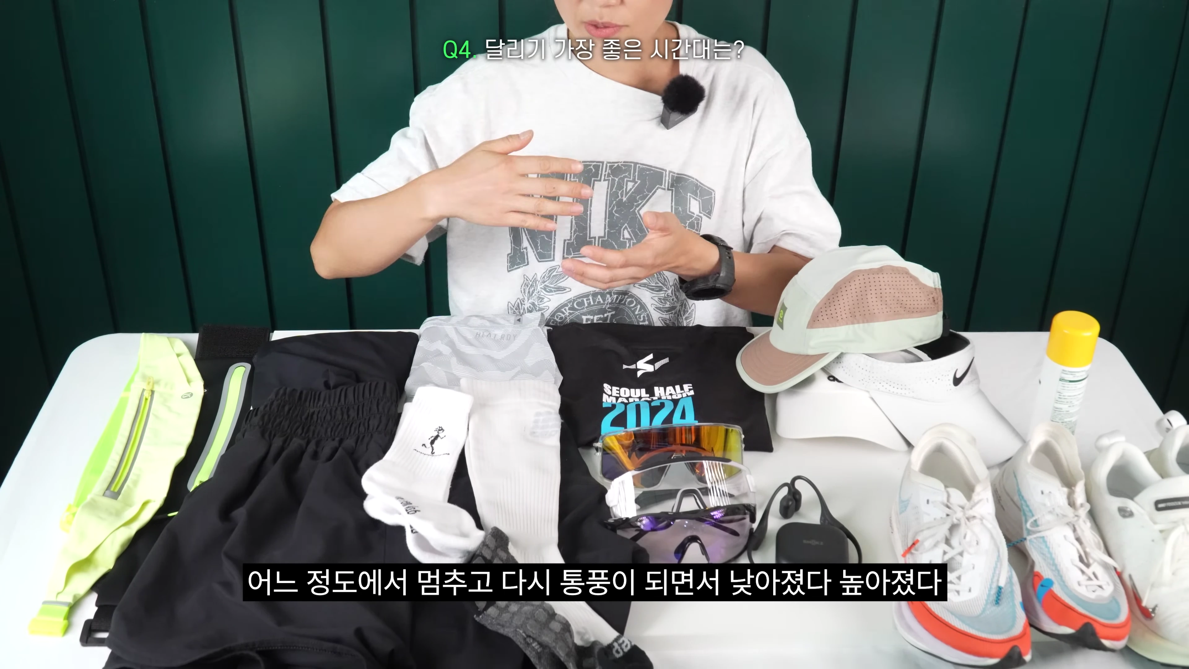 러닝 장비가 놓인 테이블 앞에 앉아 손짓하며 설명하는 사람