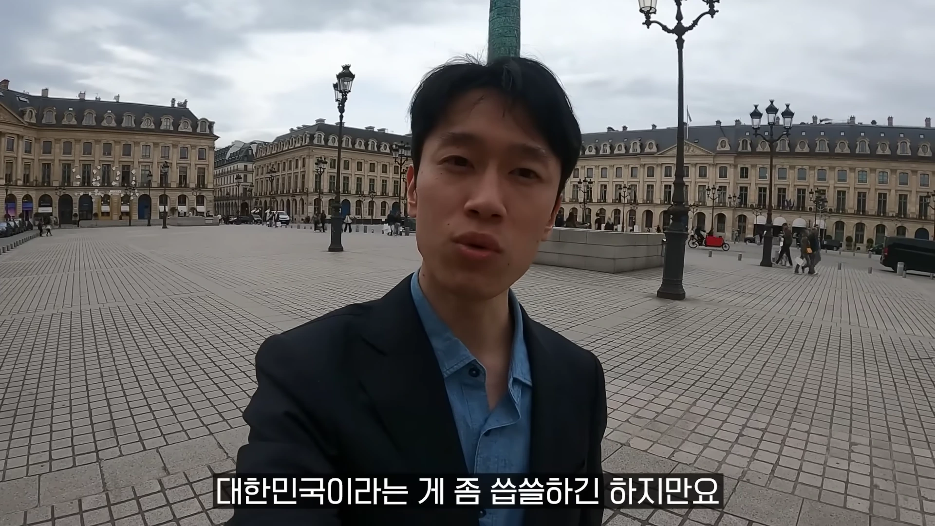 파리 방돔광장을 배경으로 카메라를 응시하며 이야기하는 남성