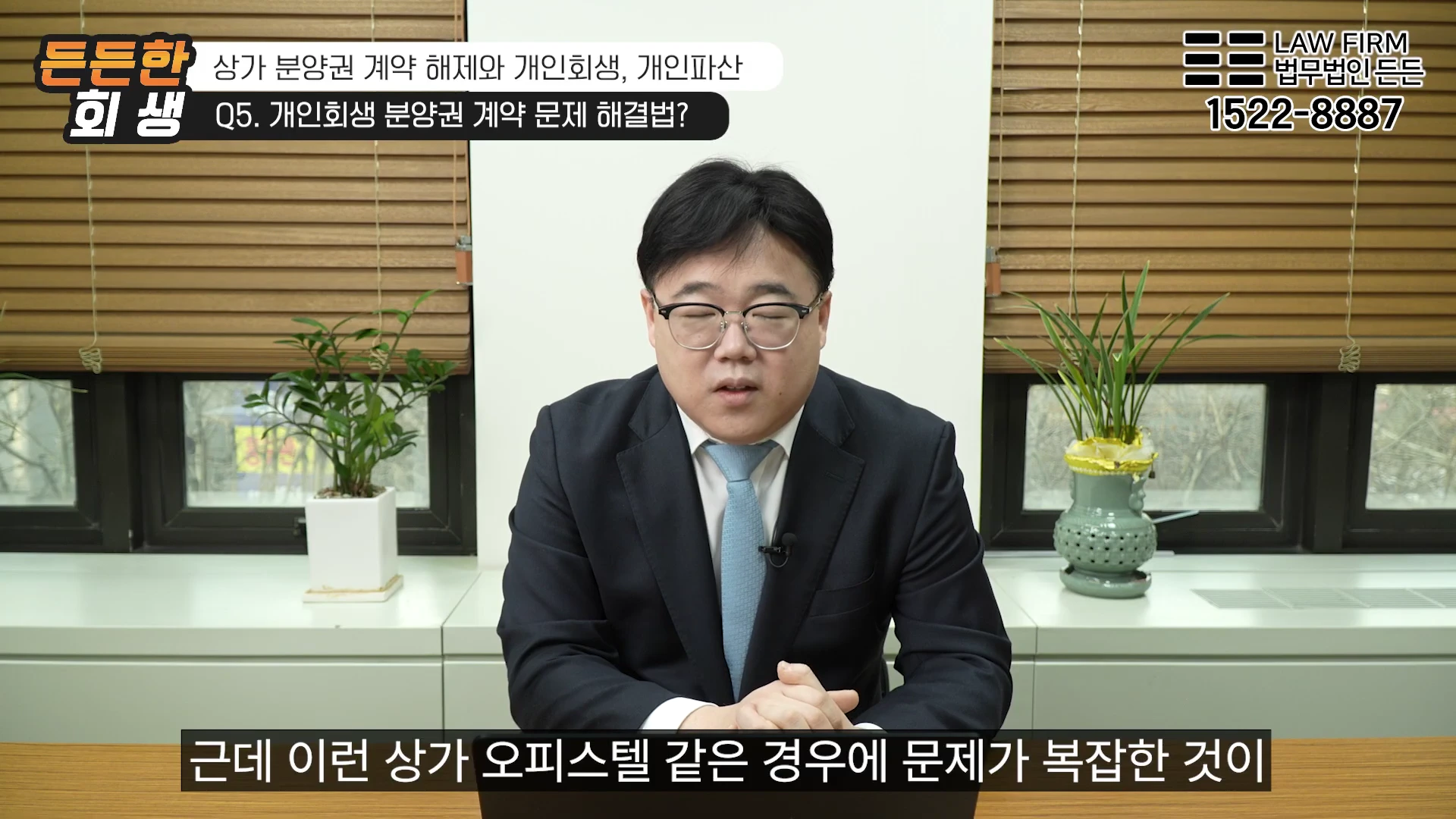 안경을 쓴 남성 변호사가 사무실 책상에 앉아 카메라를 보며 법률 상담을 진행하고 있다.