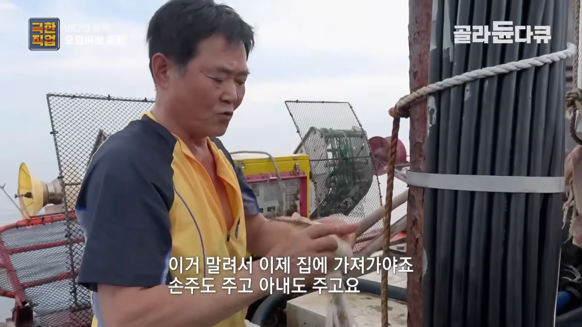 어선 갑판 위에서 노란색 작업복을 입은 중년 남성이 오징어를 손질하고 있는 모습