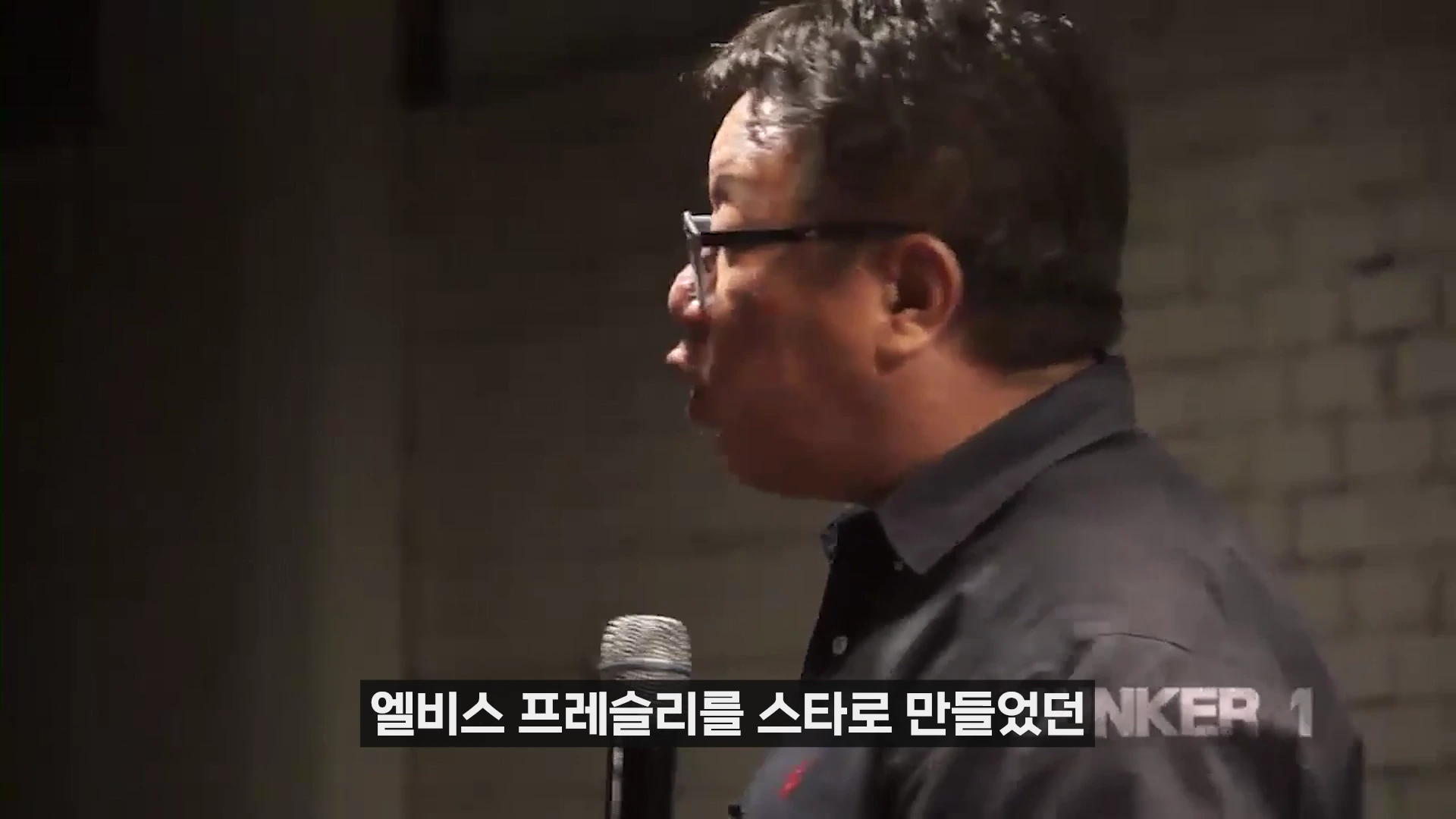 안경을 쓴 남성이 마이크를 잡고 옆모습을 보이며 강연하는 모습