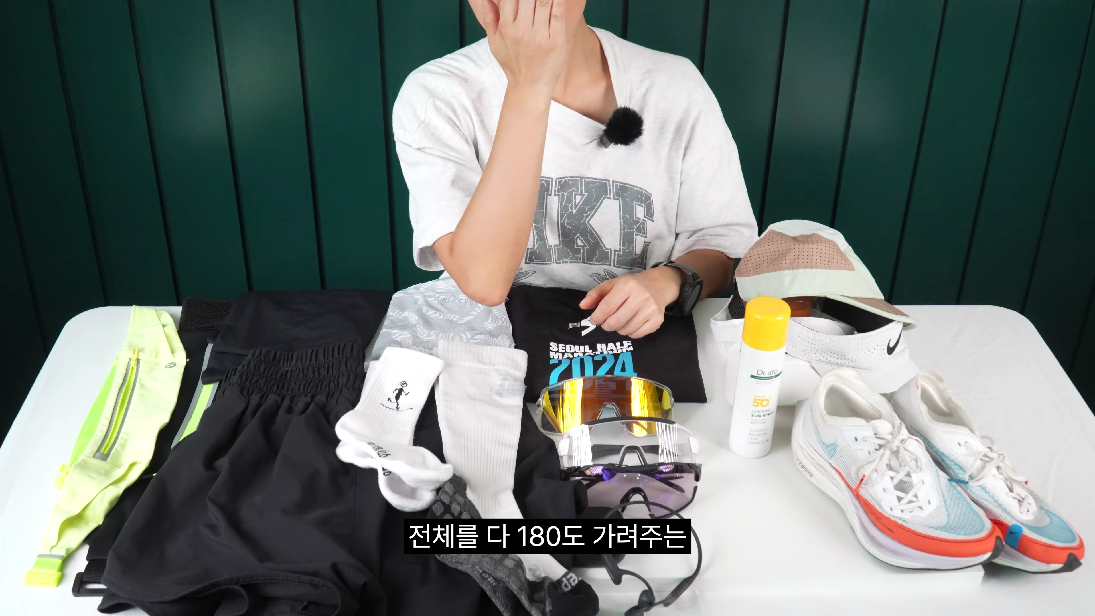 러닝 의류와 고글, 러닝화 등 다양한 장비가 놓인 테이블 앞에 앉아 있는 사람