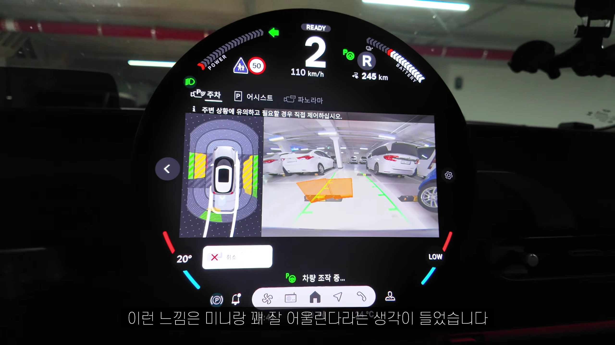 원형 디스플레이에 후방 카메라 화면과 주차 보조 그래픽이 표시된 차량 내부 모습