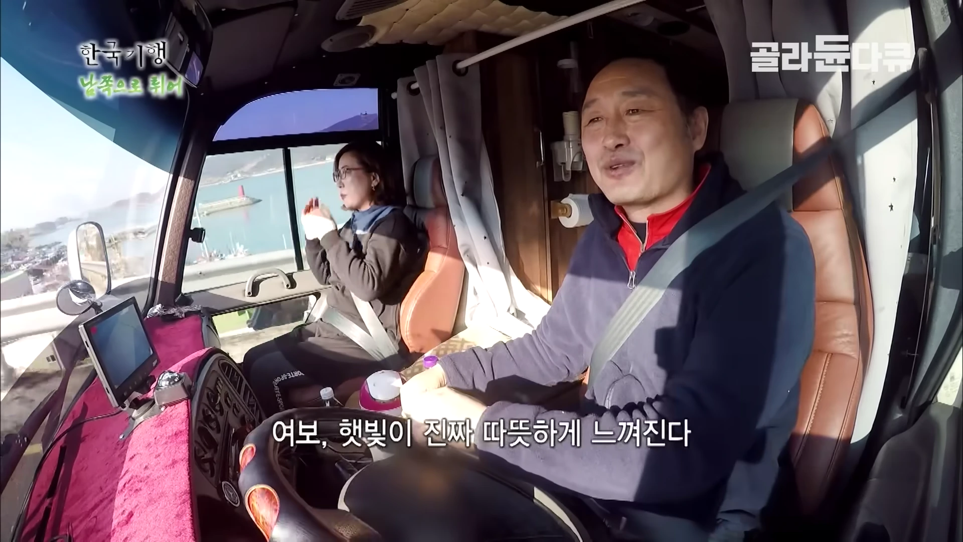 캠핑카 운전석과 조수석에 앉아 대화를 나누는 중년 부부의 모습