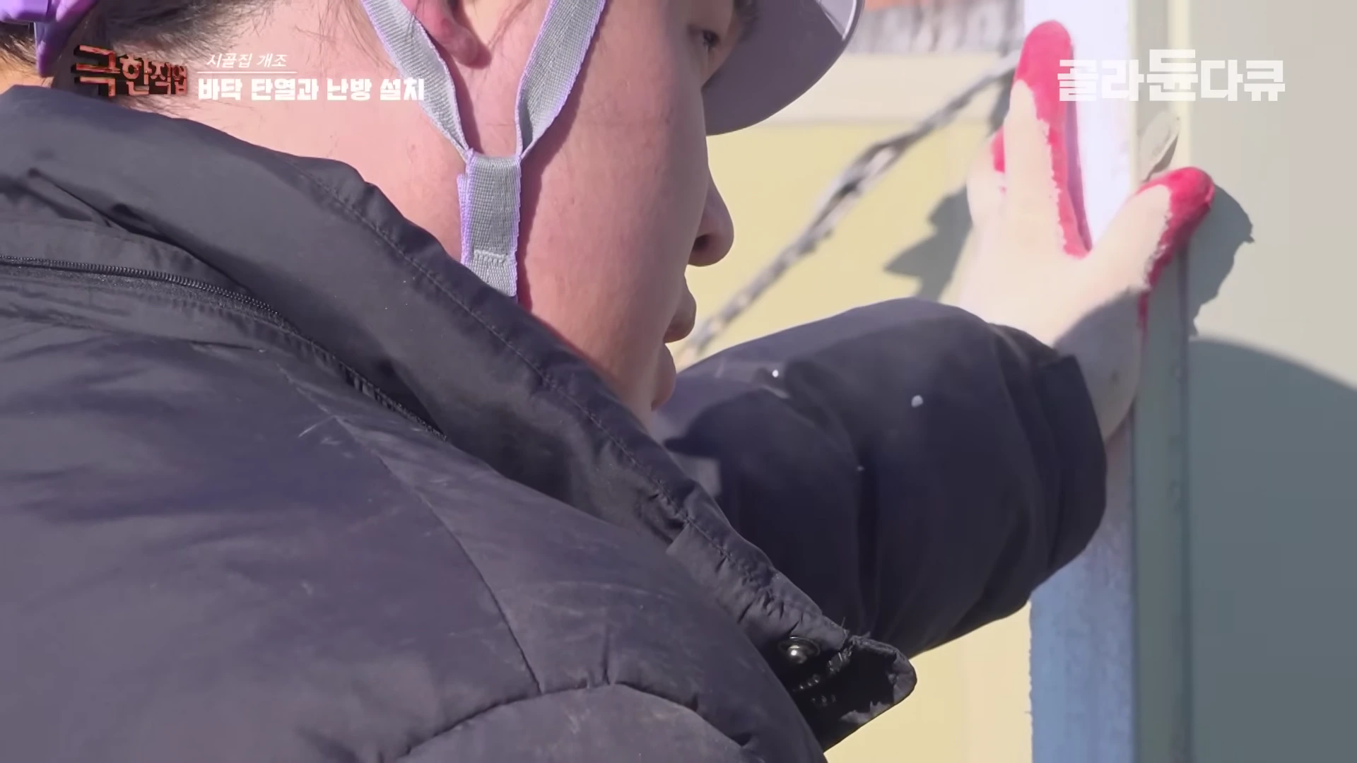 안전모를 쓴 작업자가 벽면에 단열재를 꼼꼼하게 부착하고 있는 모습
